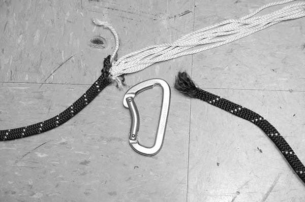 carabiner on the ground next to a split rope