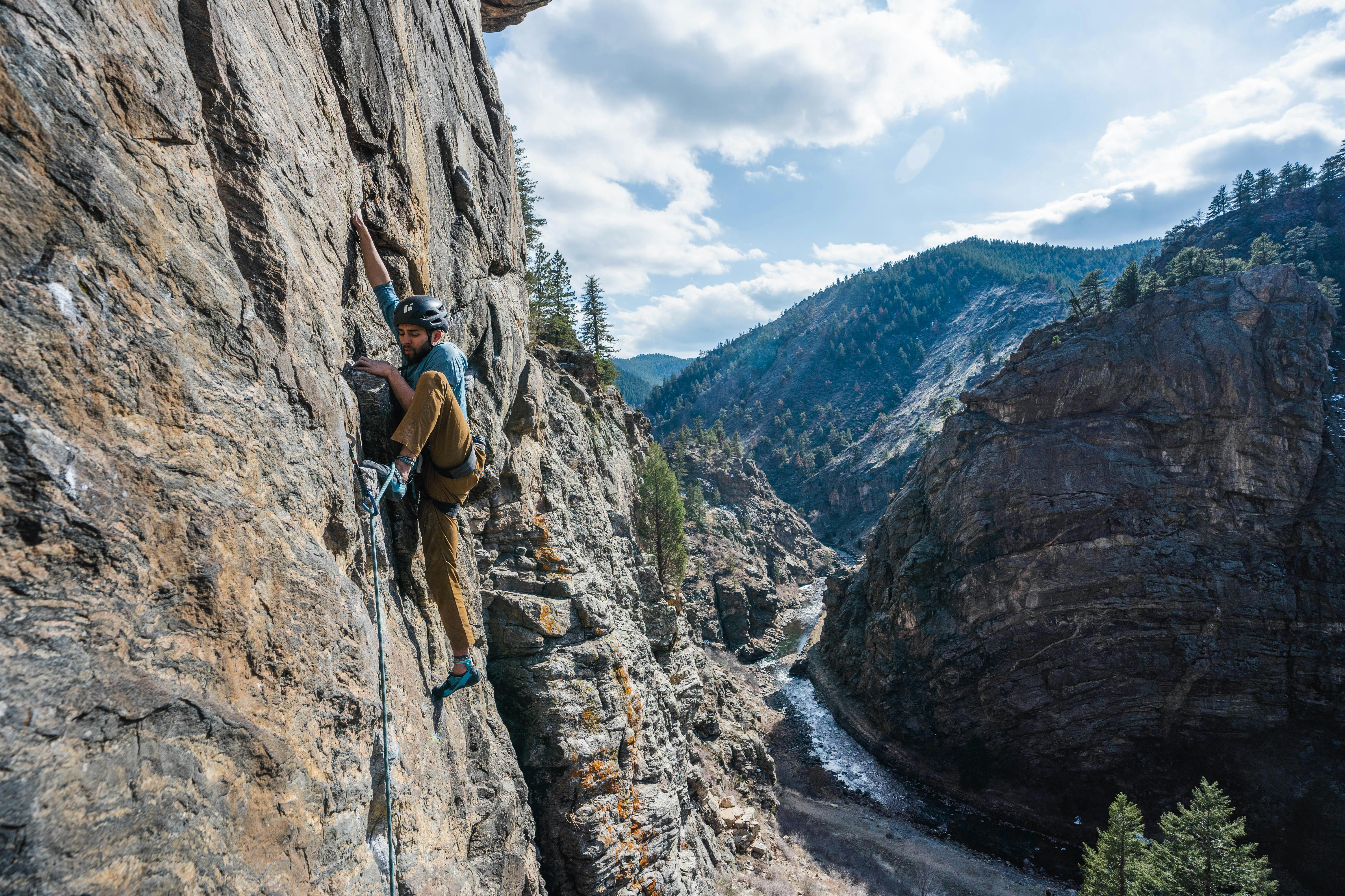 Black Diamond ambassador Xavier Bravo rock climbing in the Rocklock Climbing pants with a scenic canyon in the background. 