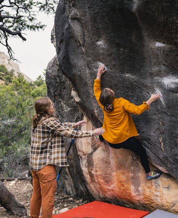 A climber attempting a boulder problem wearing the Black Diamond Project Flannel. 