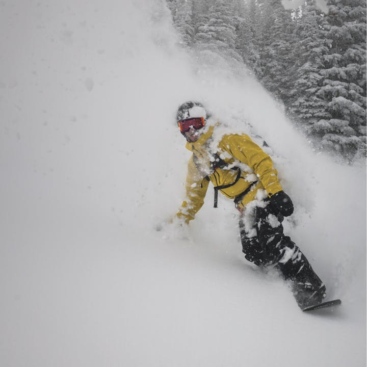 A snowboarder shreds some powder in the aspen trees wearing the Black Diamond Recon Stretch Shell.  