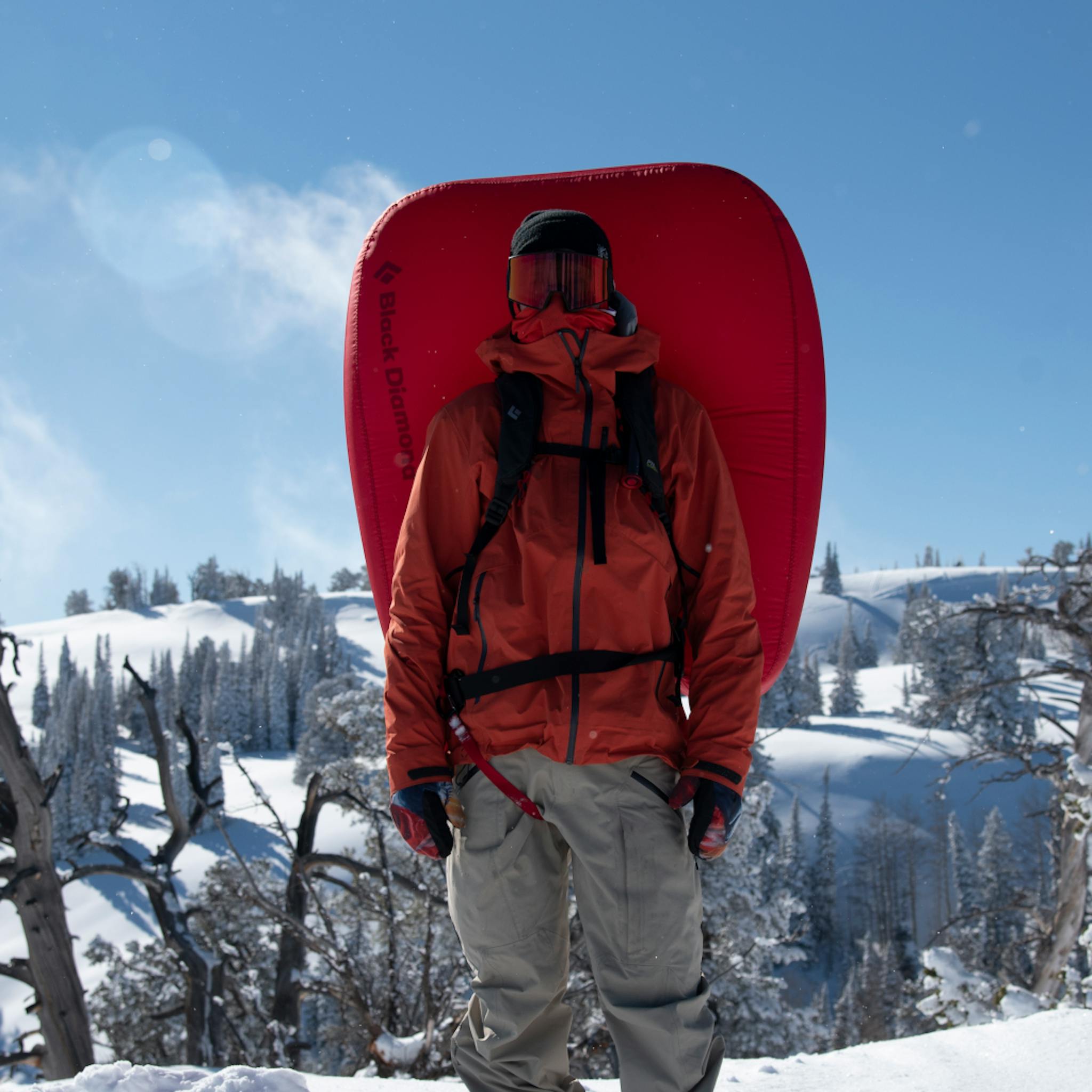 A snowboarder stands in a deloyed Jetforce split pack.