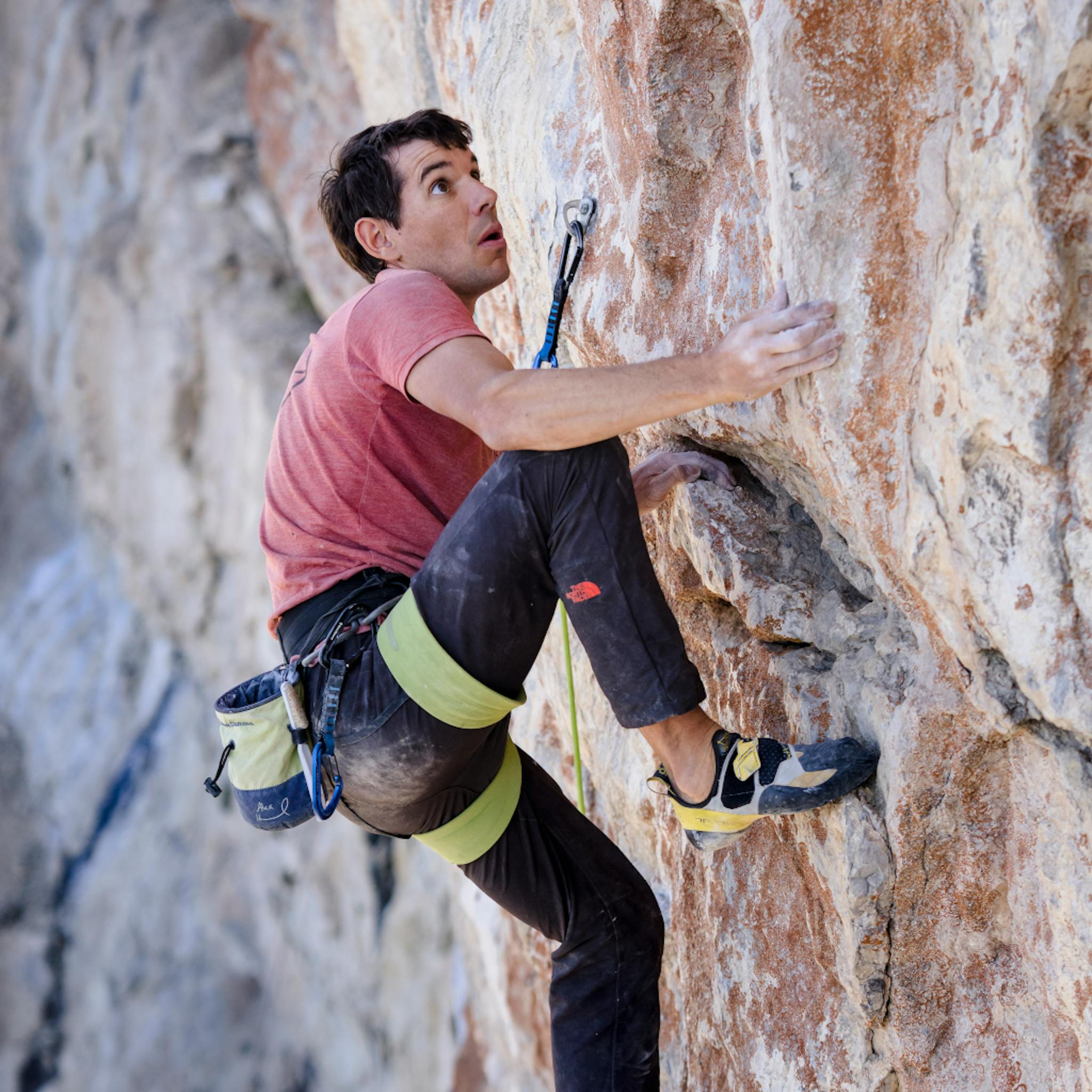BD Athlete Alex Honnold steps up on a high hold on a climb.