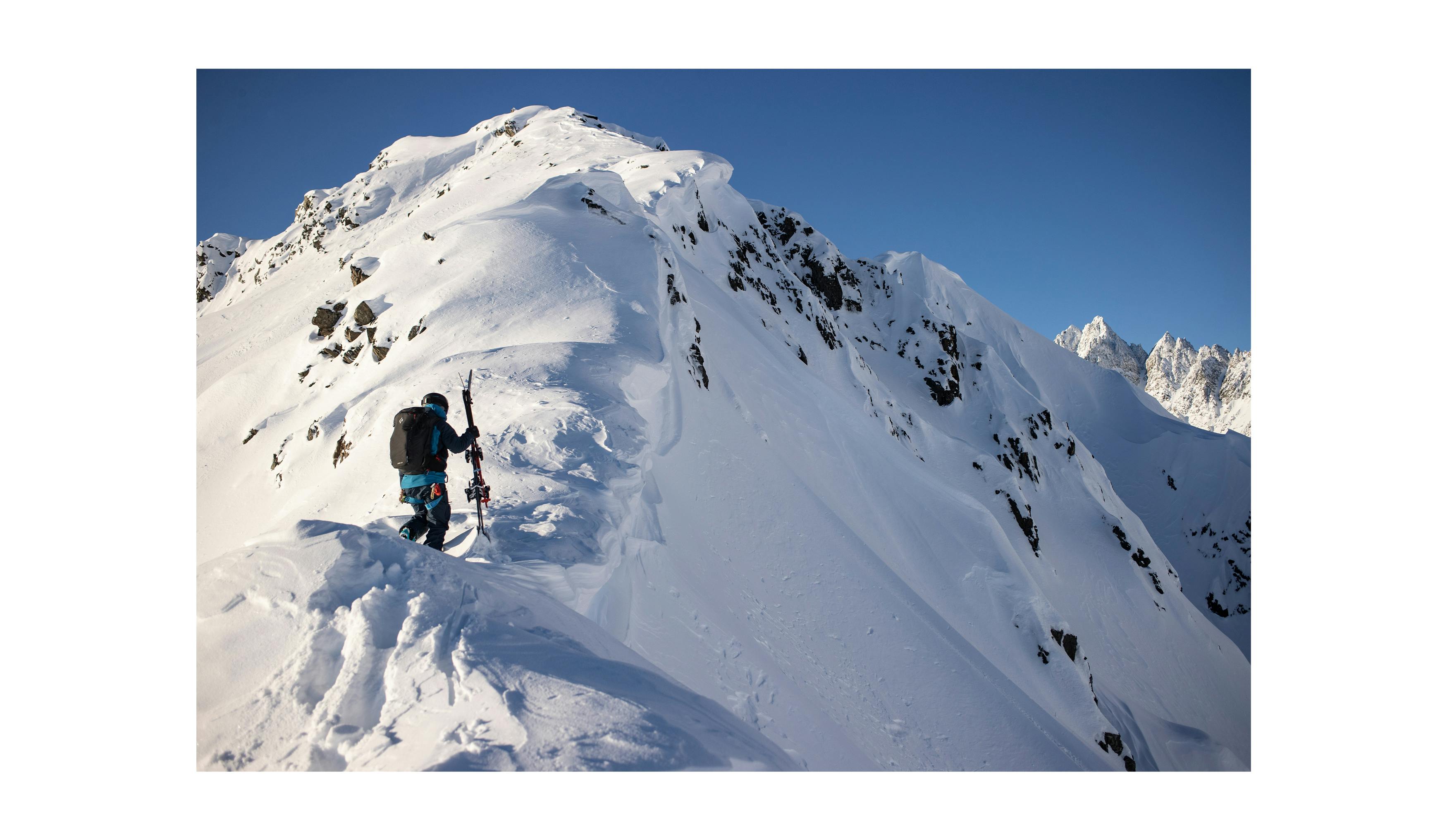 A backcountry skier traverses a ridge line of snow cornices .