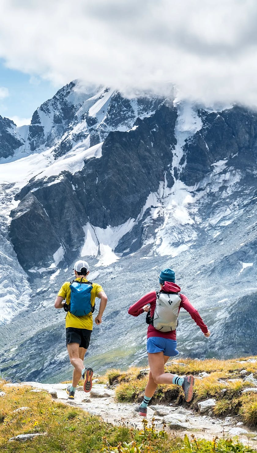 Two people running towards a glacier in switzerland