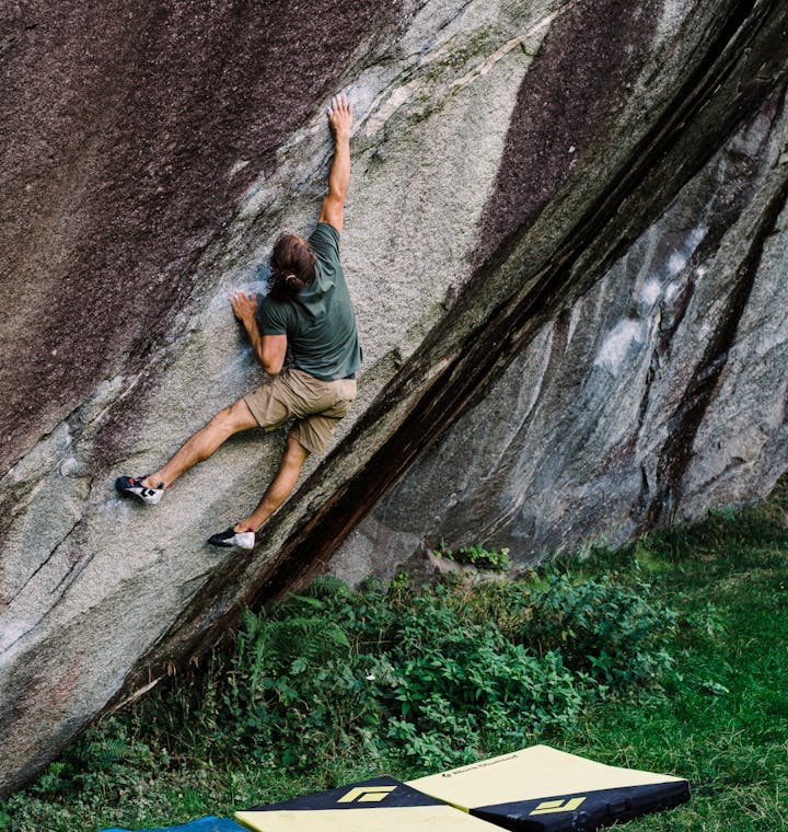 A climber sticks a deadpoint move on a boulder problem.