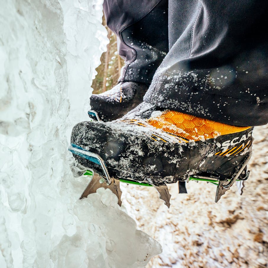 Small ice pieces come off an ice pillar as a climber kicks in with crampons.
