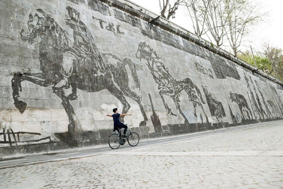 a boy biking alongside frieze