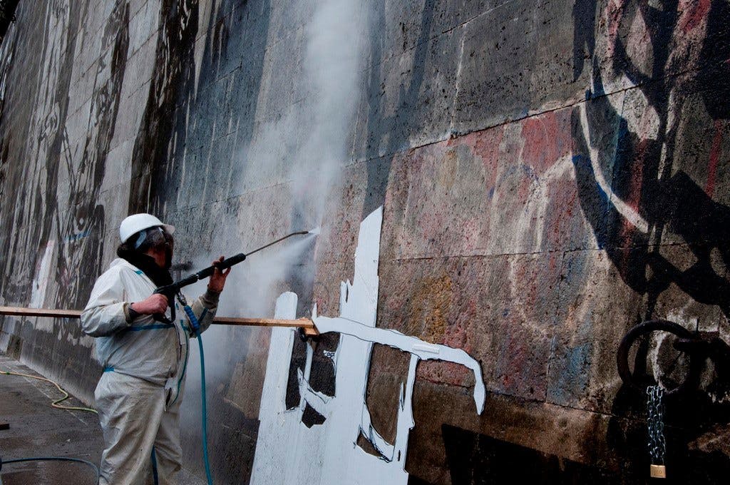 a man sandblasting artwork into a stone wall