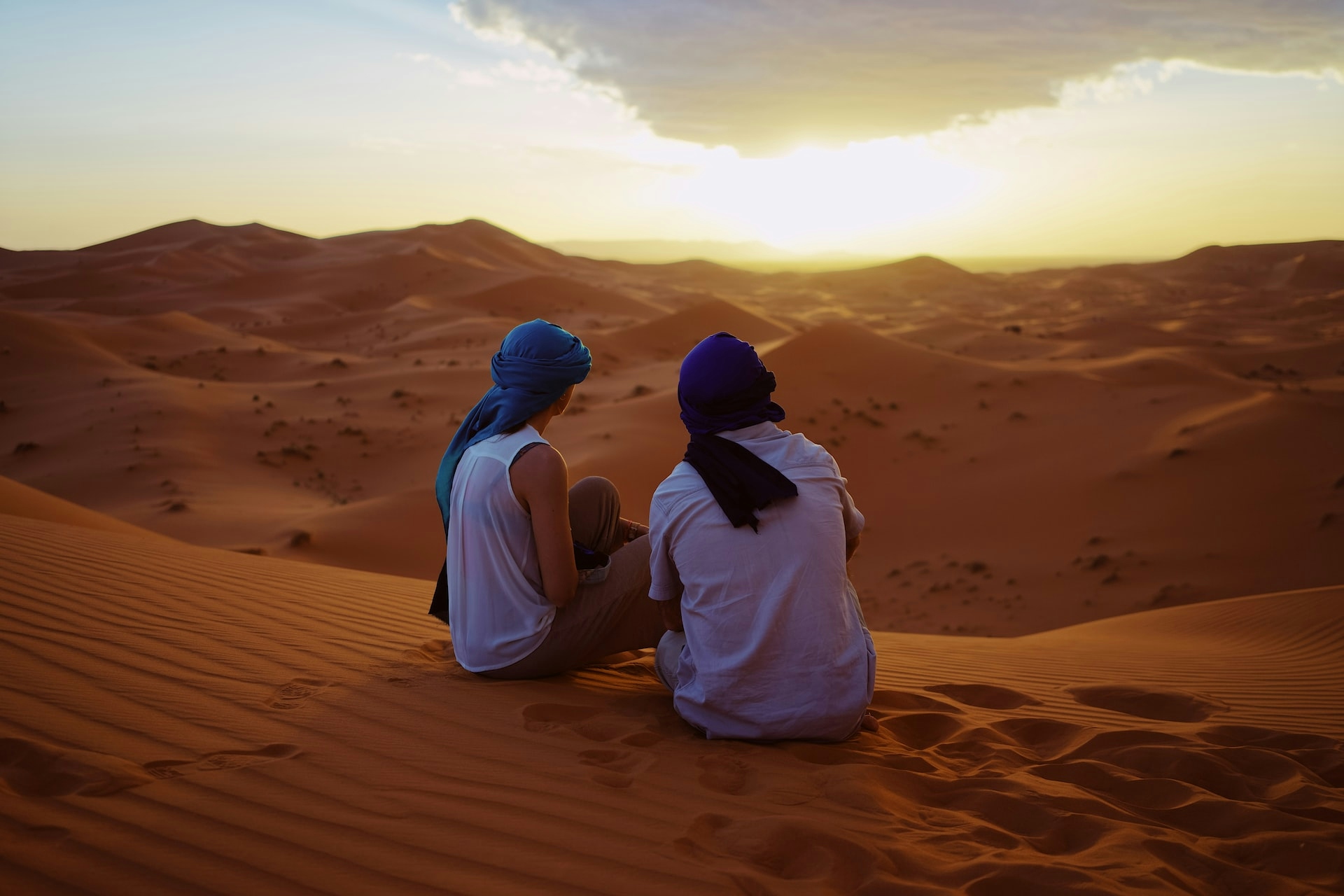 2 ragazzi seduti di spalle al tramonto nel deserto