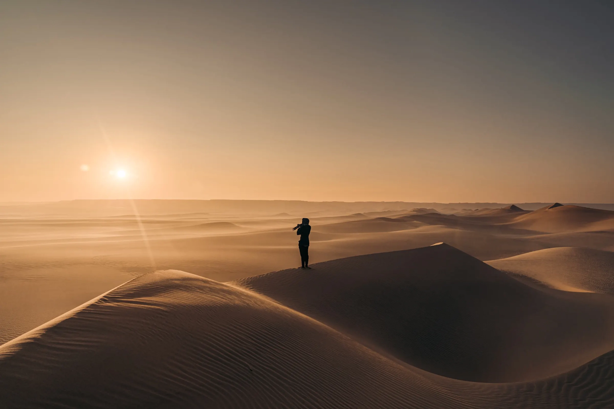 una persona in ombra al tramonto sulle dune del deserto in Egitto