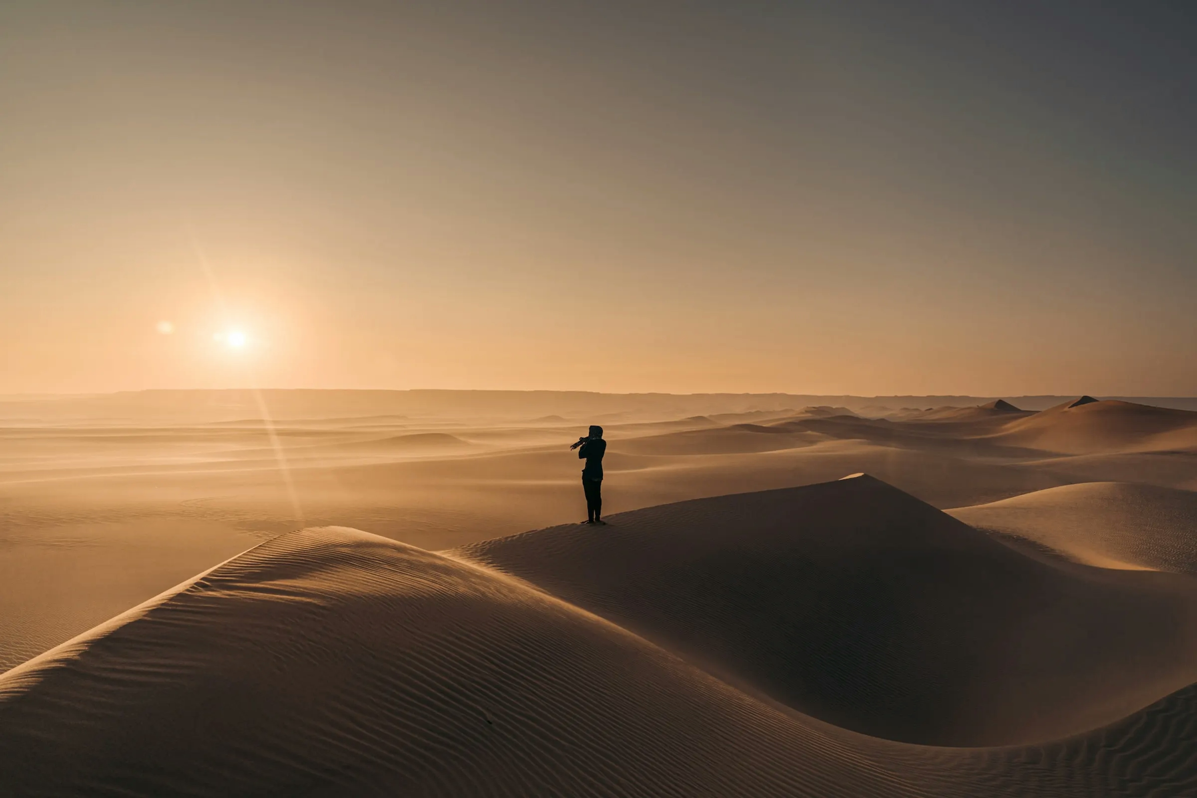 una persona in ombra al tramonto sulle dune del deserto in Egitto