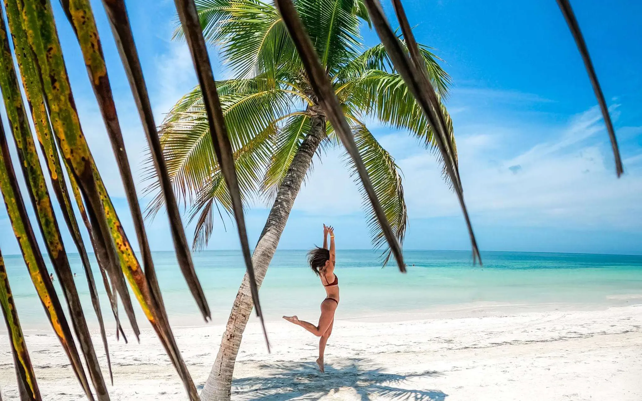 Una ragazza di spalle sotto una palma in spiaggia in Repubblica Dominicana