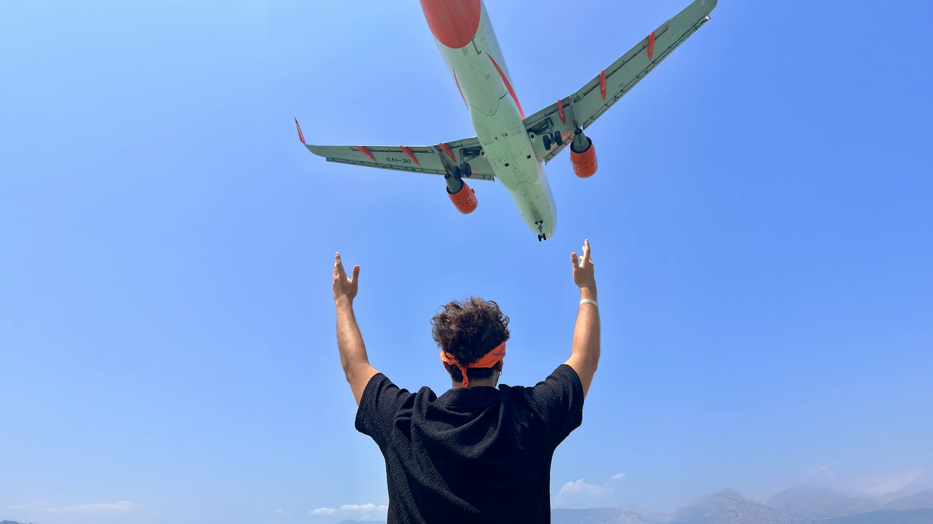 Ragazzo che guarda una aereo che vola nel cielo a Corfù