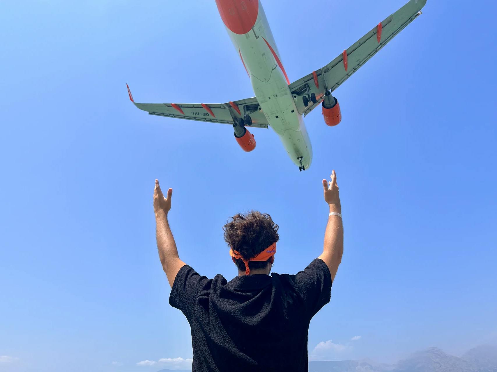 Ragazzo che guarda una aereo che vola nel cielo a Corfù