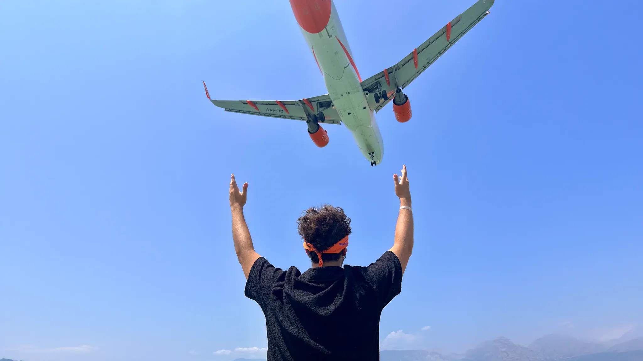 Ragazzo che guarda una aereo che vola nel cielo a Corfù