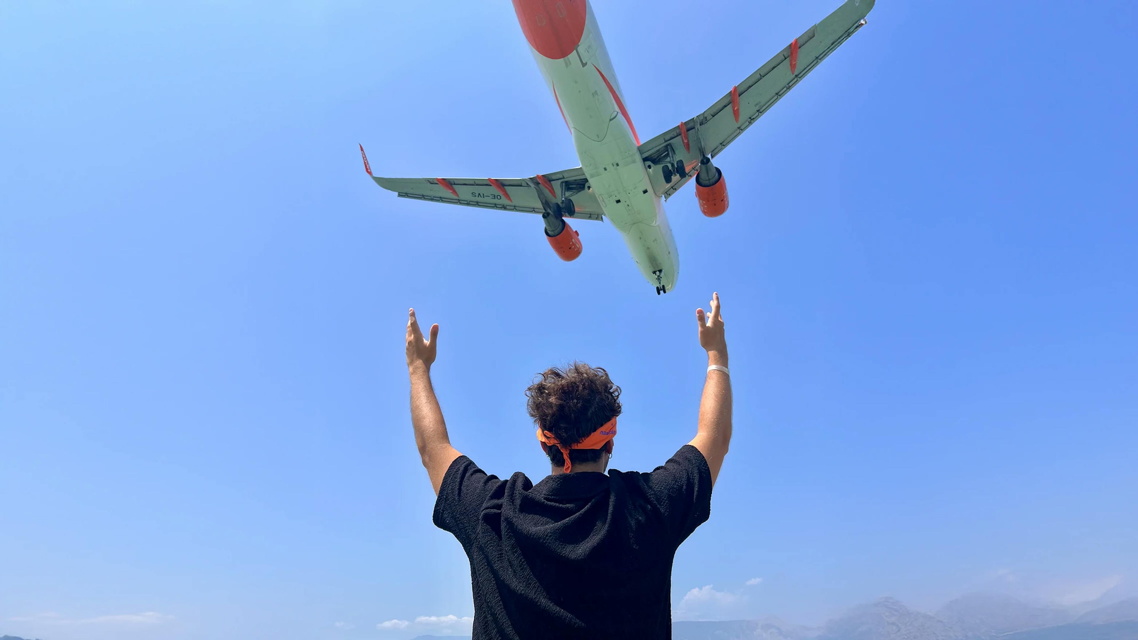 Ragazzo che guarda una aereo che vola nel cielo a Corfù