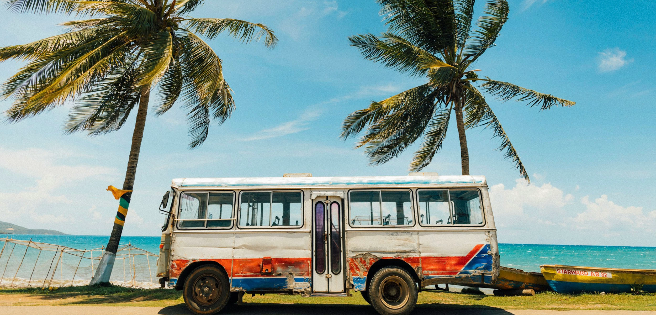 Bus su una spiaggia in Giamaica in mezzo a due palme