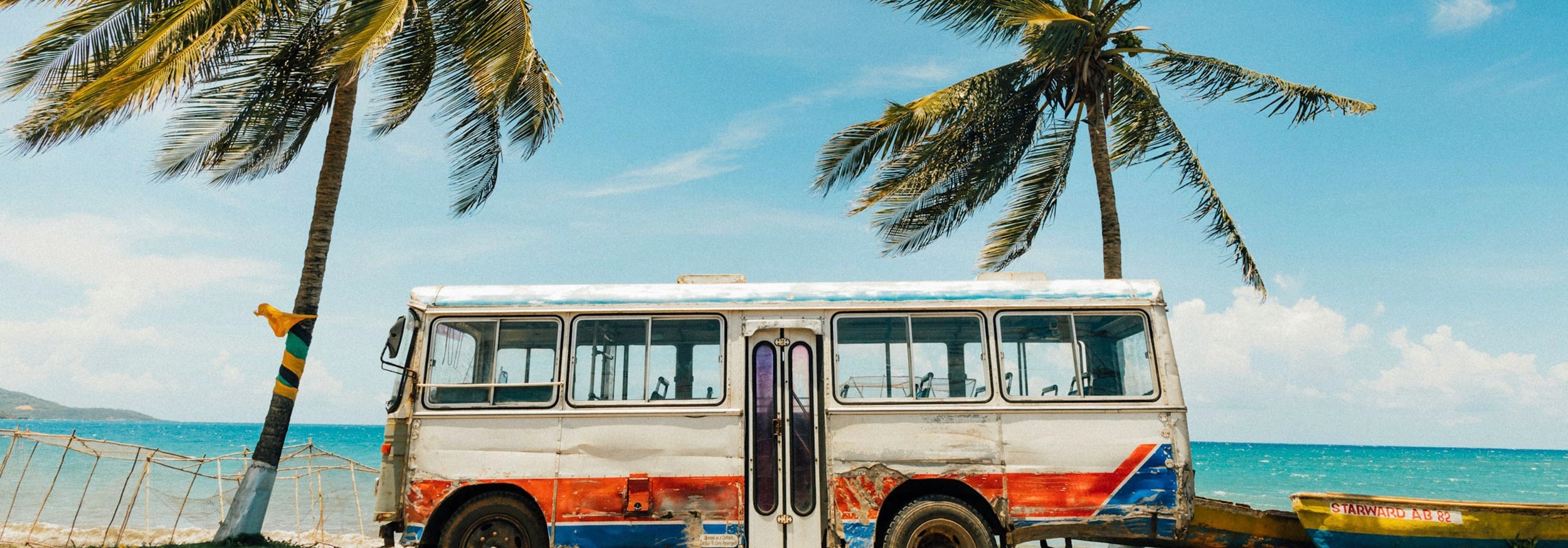 Bus su una spiaggia in Giamaica in mezzo a due palme