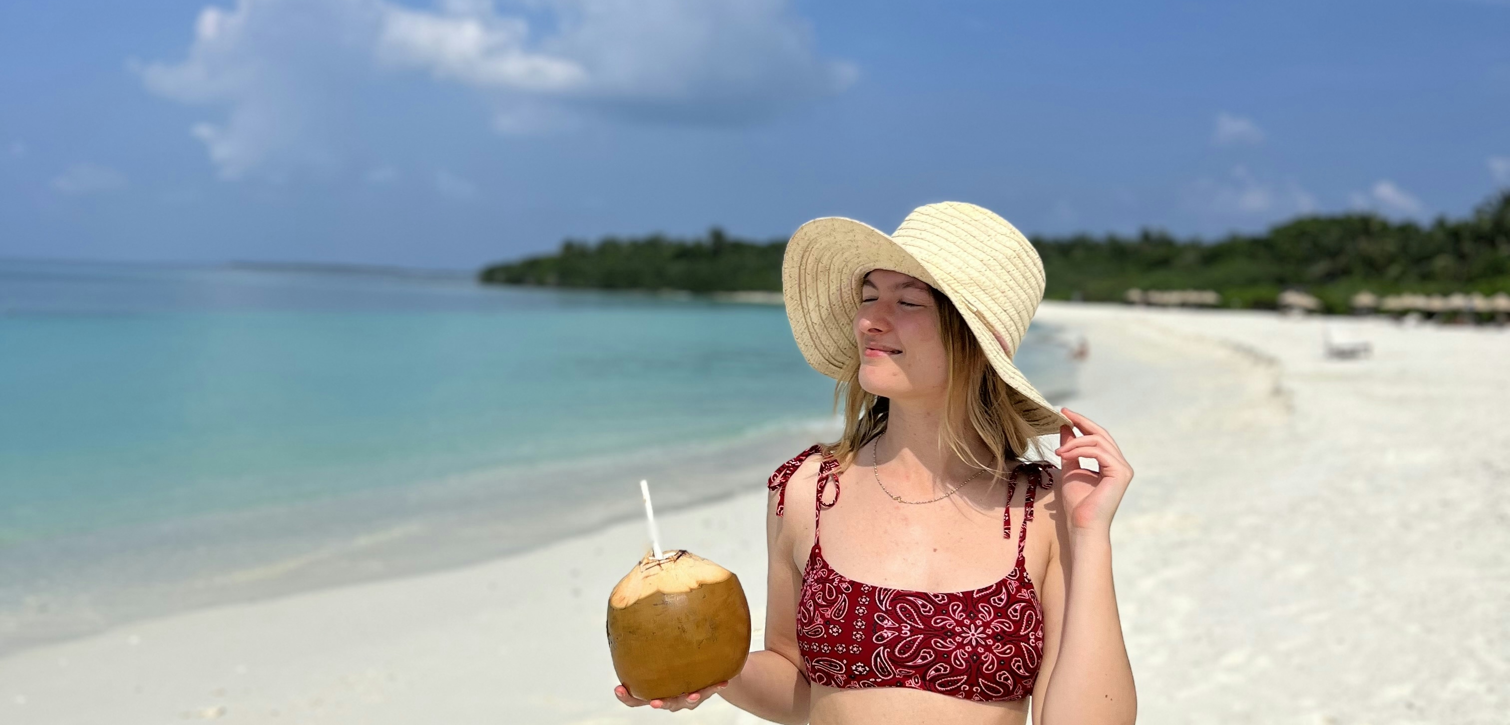 ragazza che sorseggia un cocco in spiaggi alle maldive