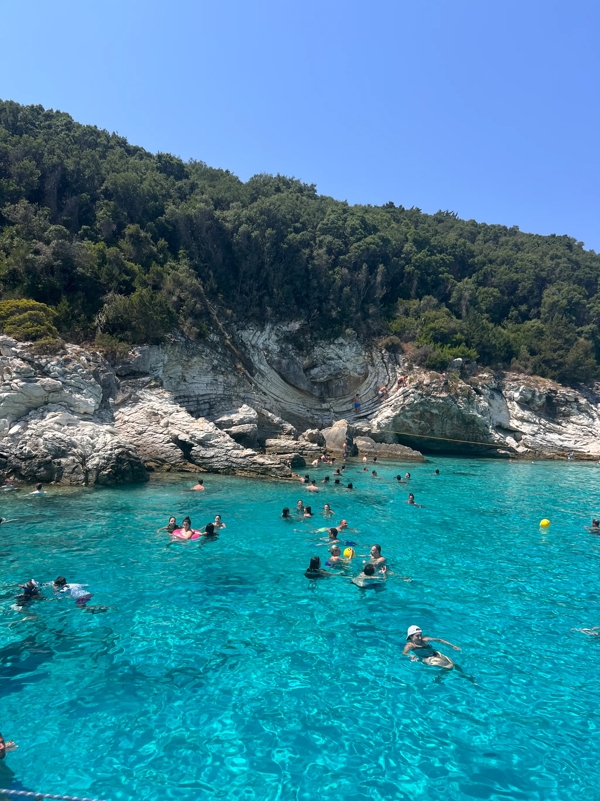 Persone che nuotano nell'acqua cristallina di Paxos