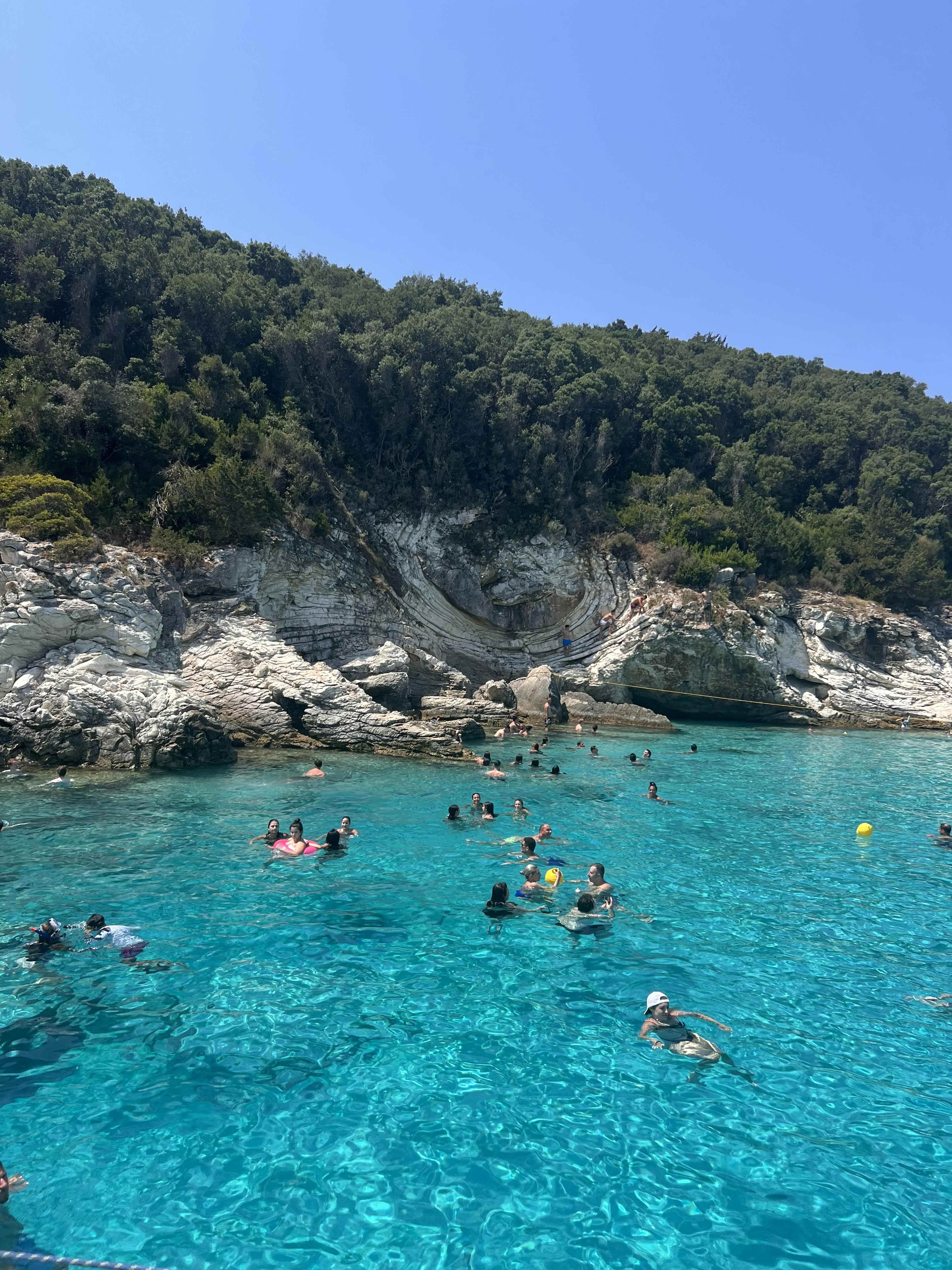 Persone che nuotano nell'acqua cristallina di Paxos