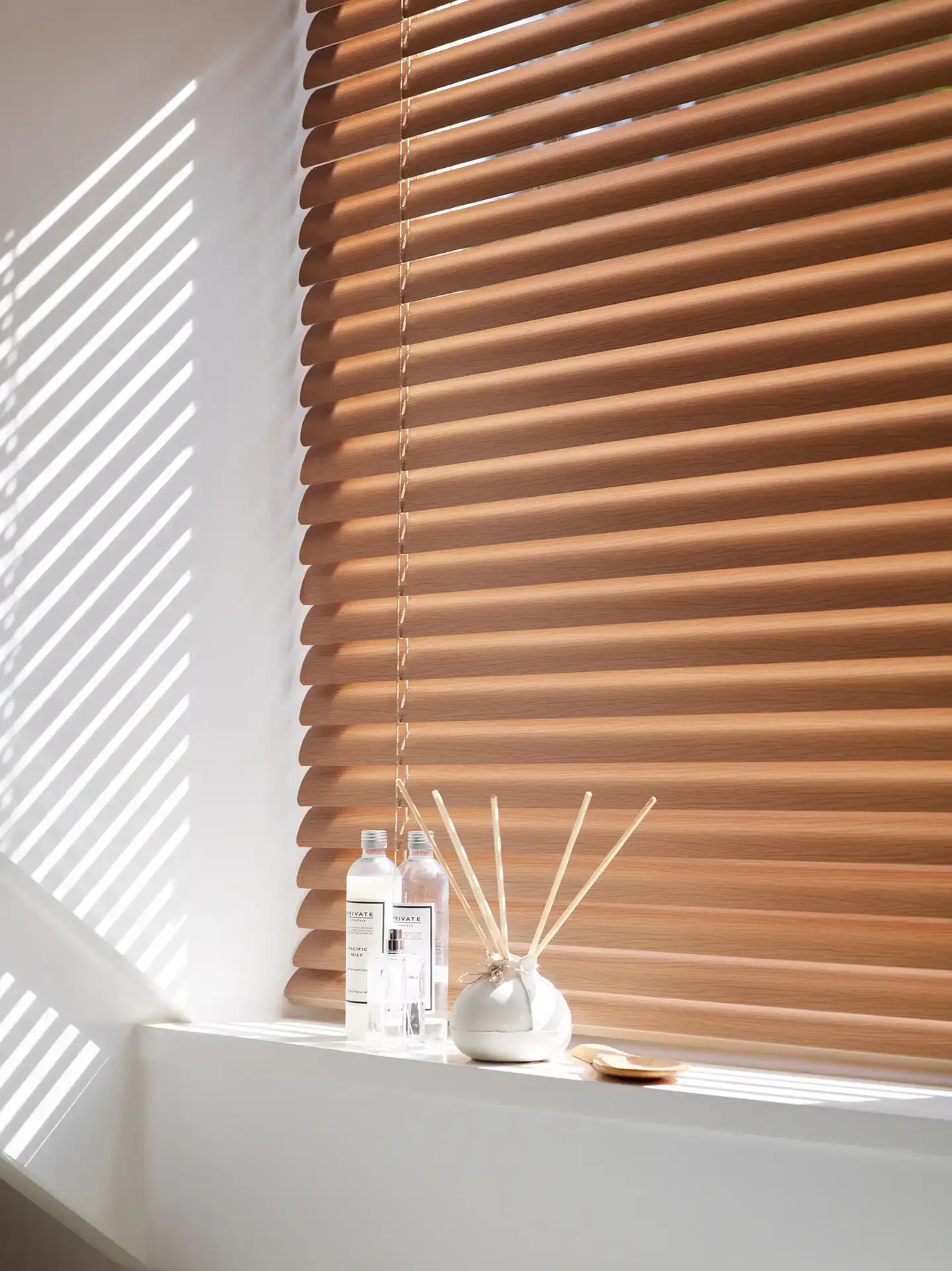 Horizontal aluminium venetian blinds filtering daylight across a corner 