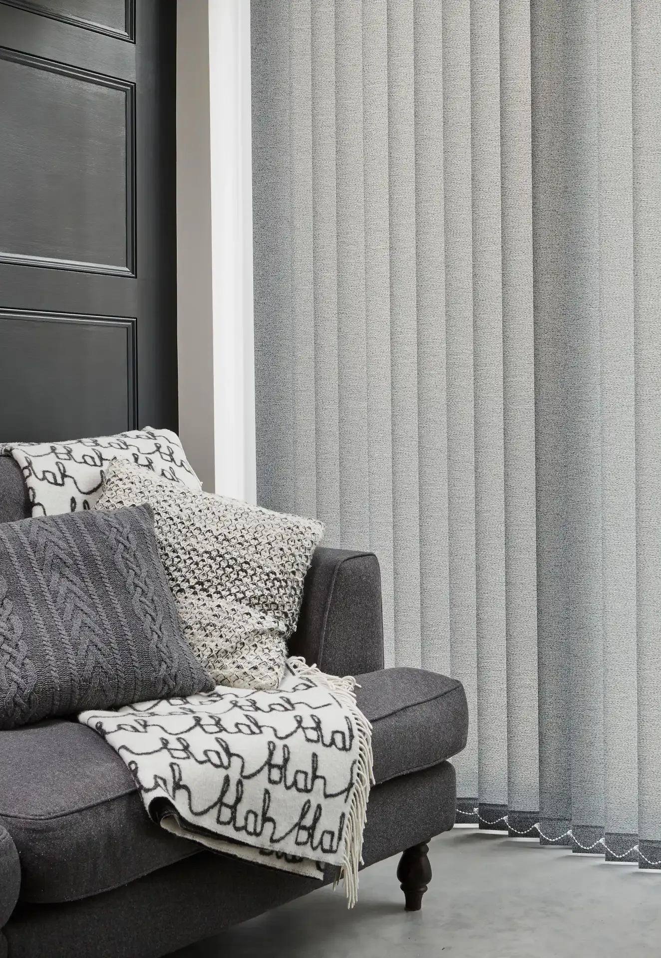 Vertical grey blinds covering a tall window