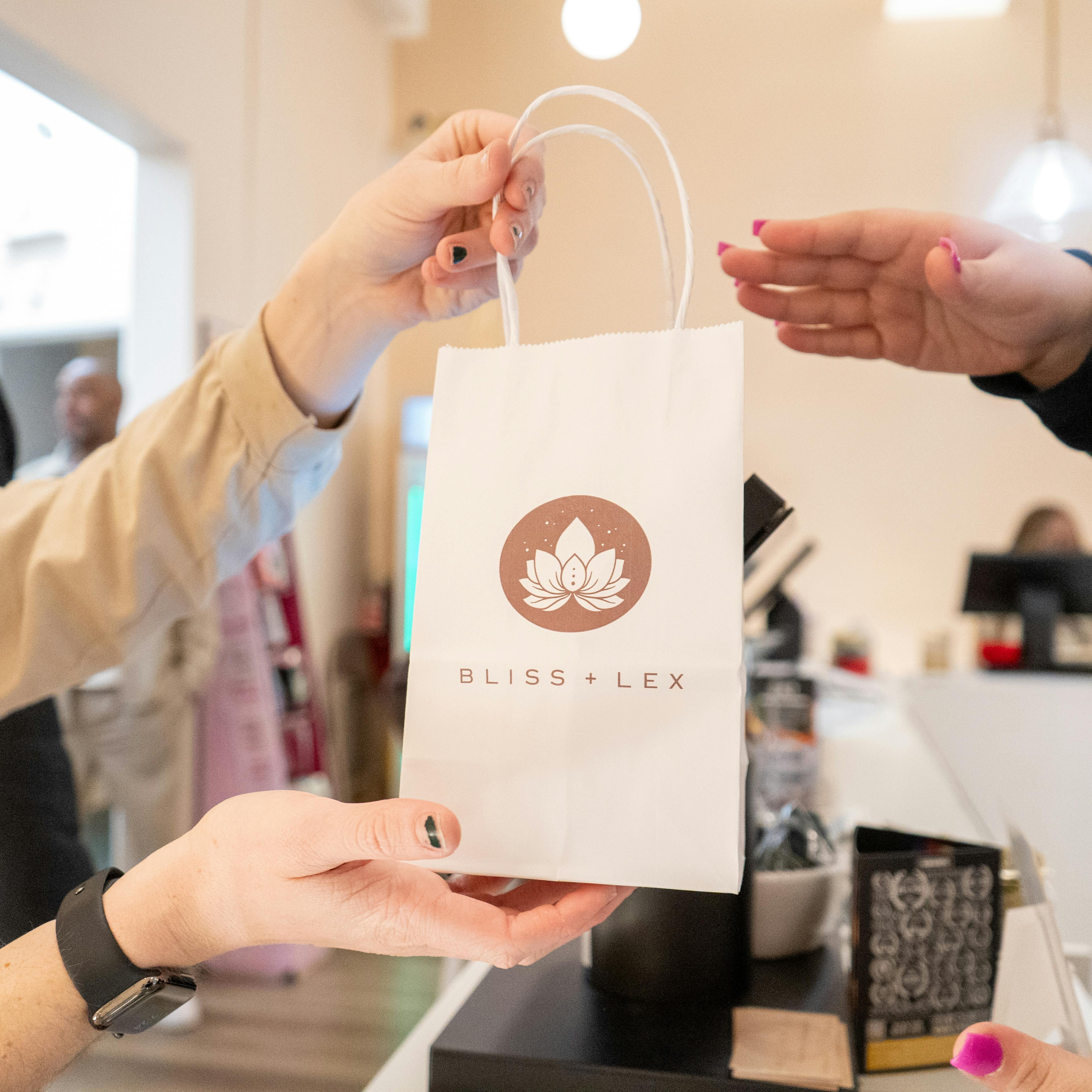 Budtender handing off a Bliss and Lex bag to a customer. 