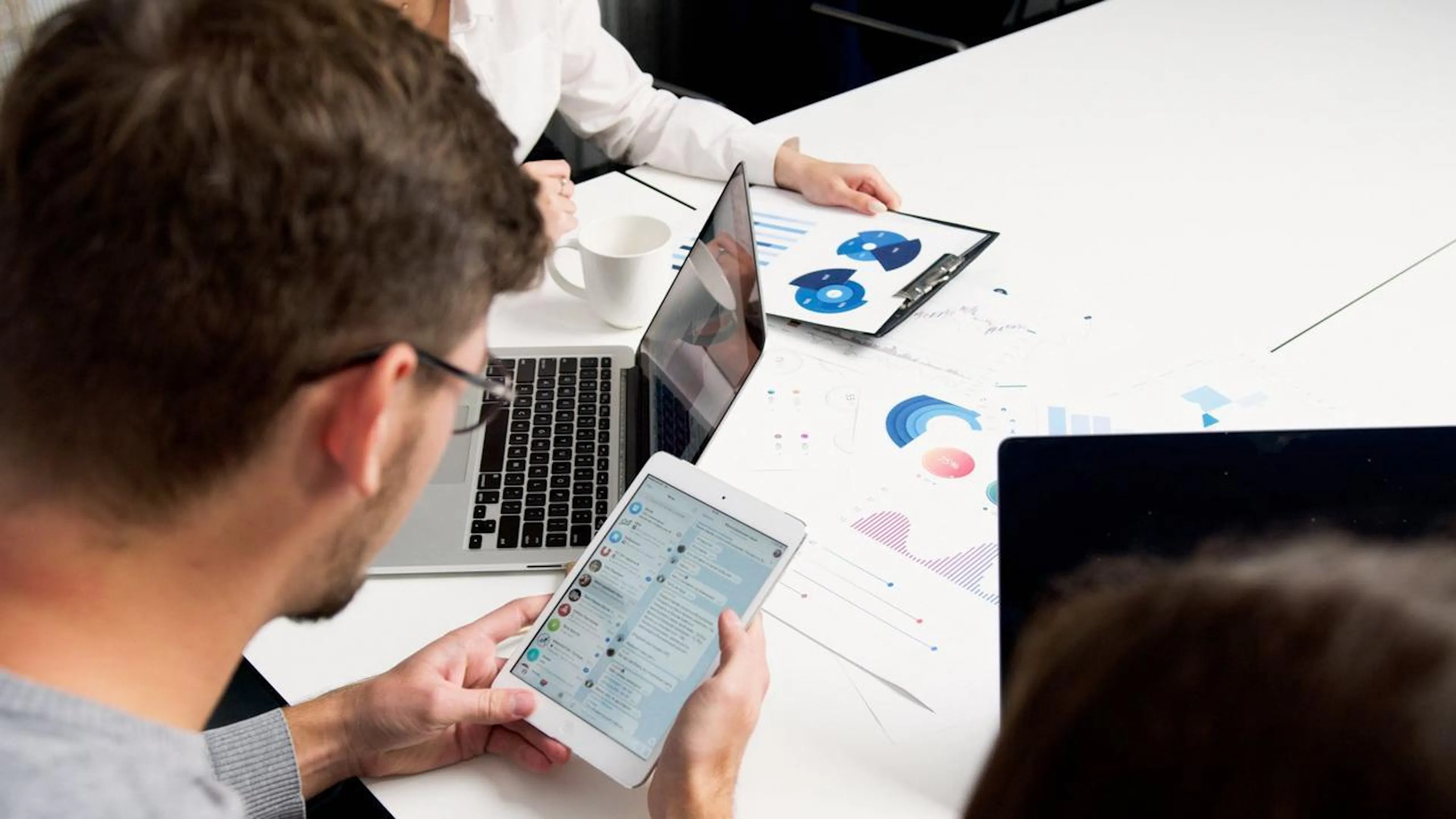 Equipe de atendimento ao cliente em um ambiente de trabalho moderno, utilizando múltiplos monitores com sistemas integrados e gerenciando conversas em diferentes canais, incluindo WhatsApp Business.