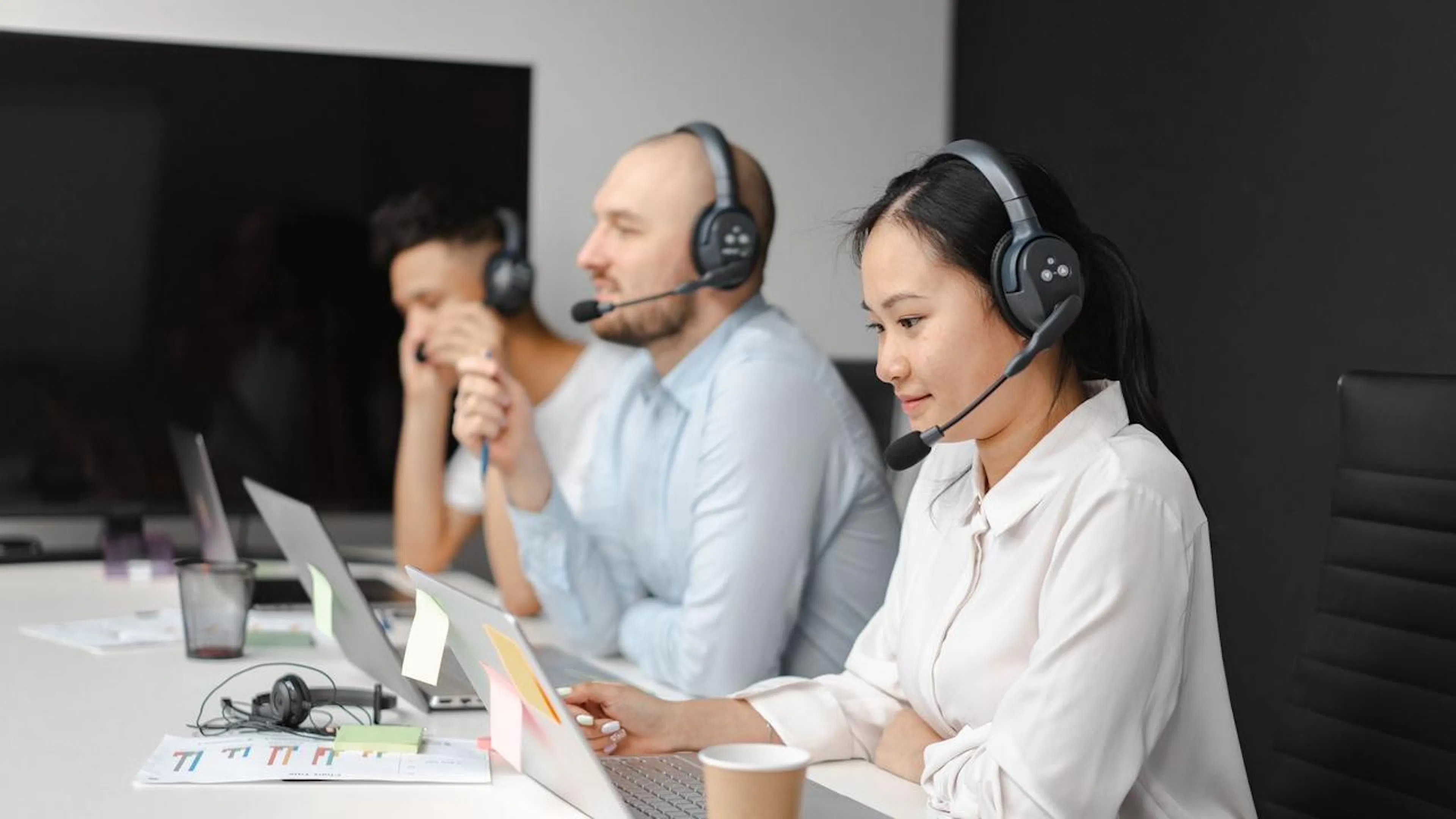 Equipe de atendimento ao cliente utilizando ferramentas de IA em computadores para otimizar suas interações e suporte.