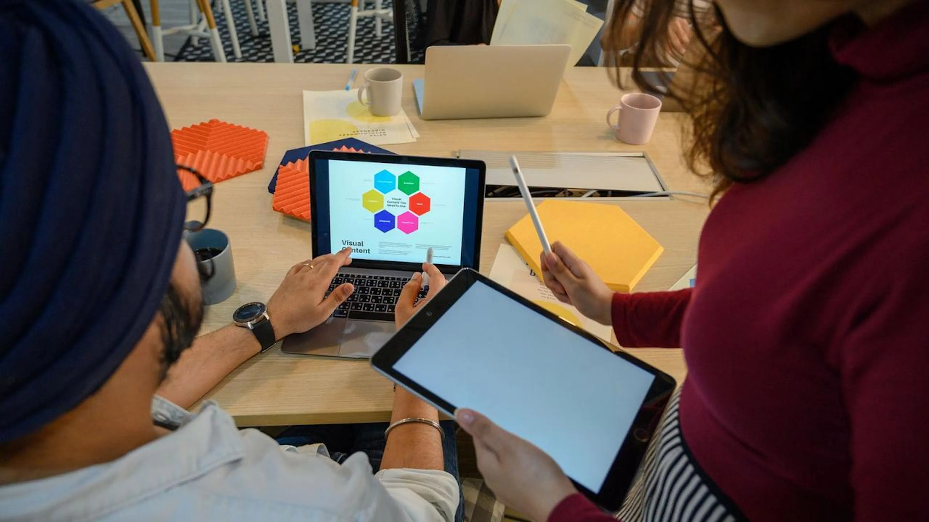 Uma equipe de profissionais em um escritório moderno, colaborando em torno de computadores e smartphones, com gráficos e interfaces de IA em suas telas, simbolizando a comunicação e a gestão otimizadas.