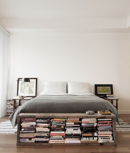 Colocar un mueble a los pies de la cama para almacenar libros.
