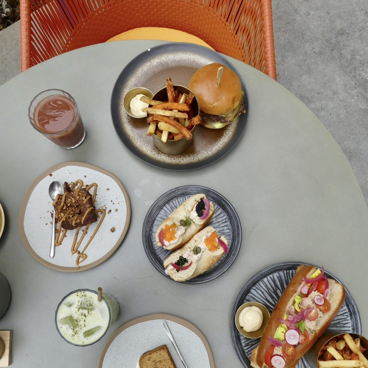 Table grise et chaise orange. Divers plats sont présents sur la table