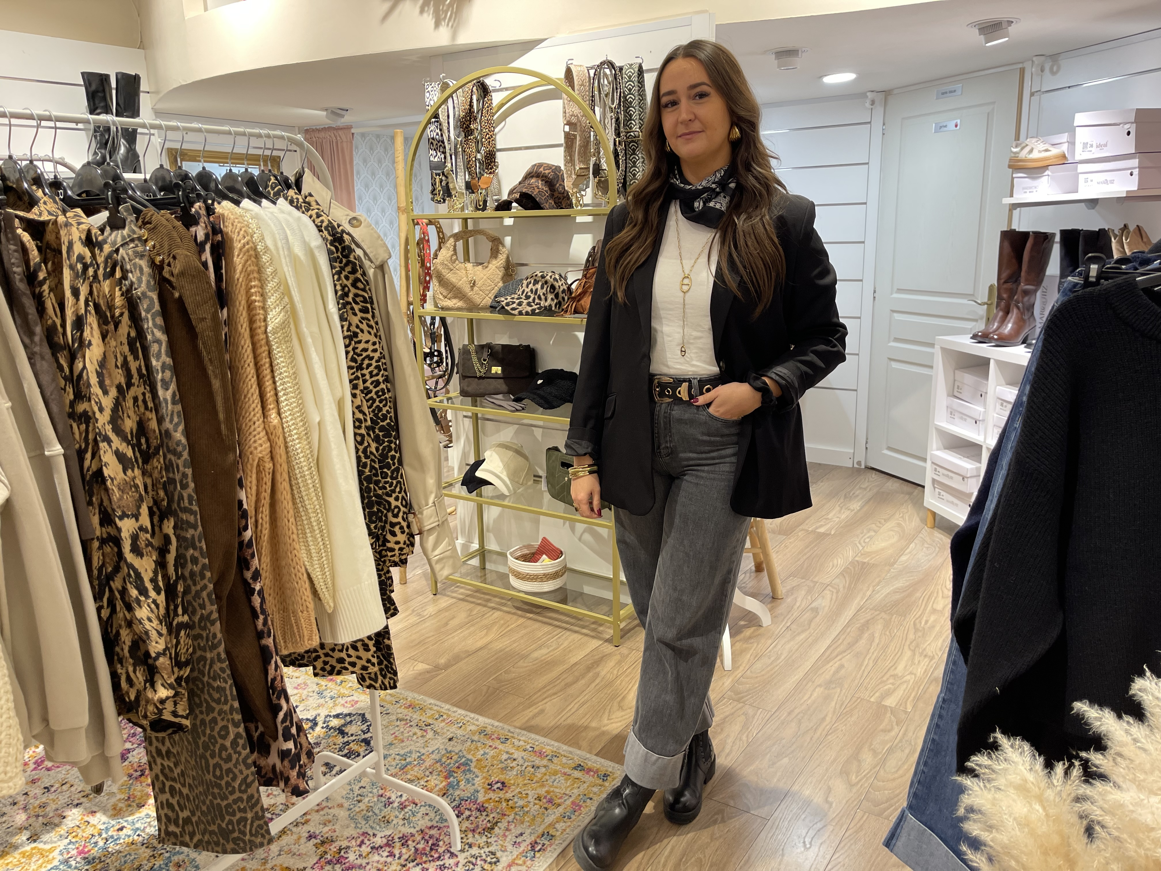 Une jeune femme debout dans une boutique de vêtements