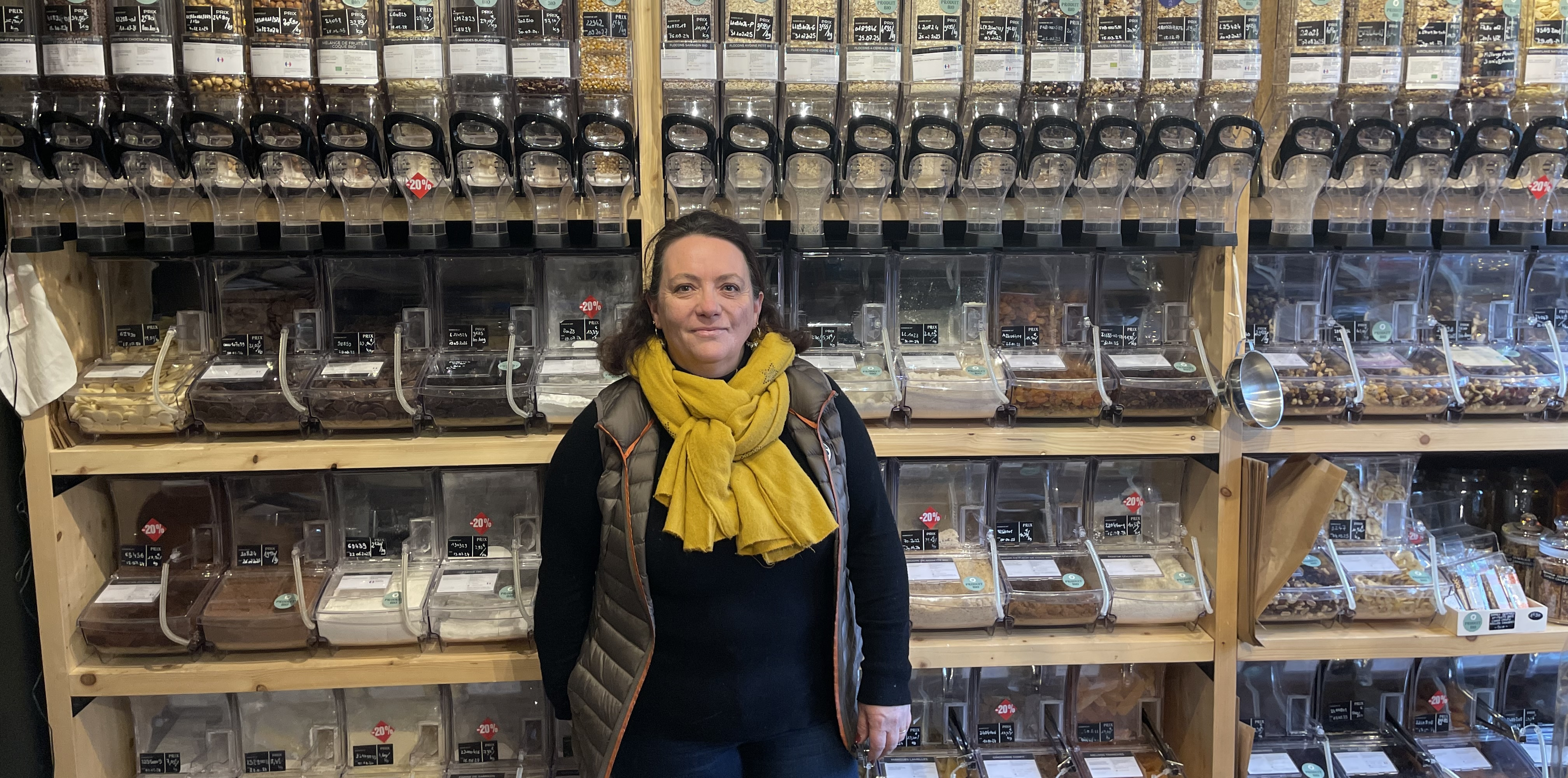 Une femme pose devant des distributeurs d'aliments en vrac
