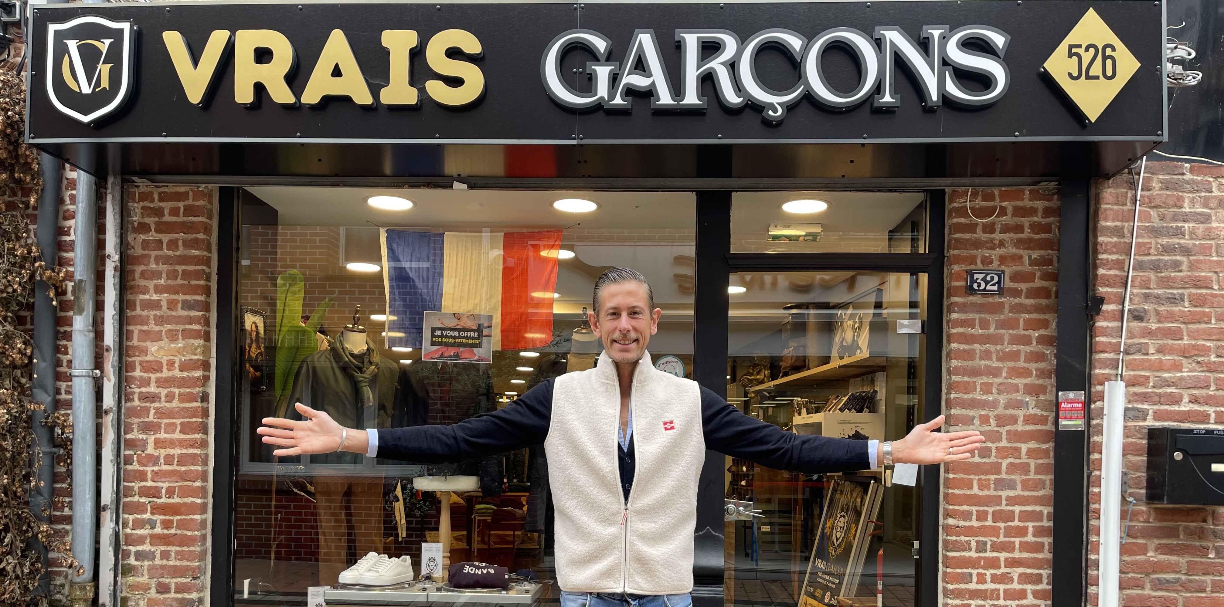 Un homme se tient debout devant une enseigne de vêtements pour homme