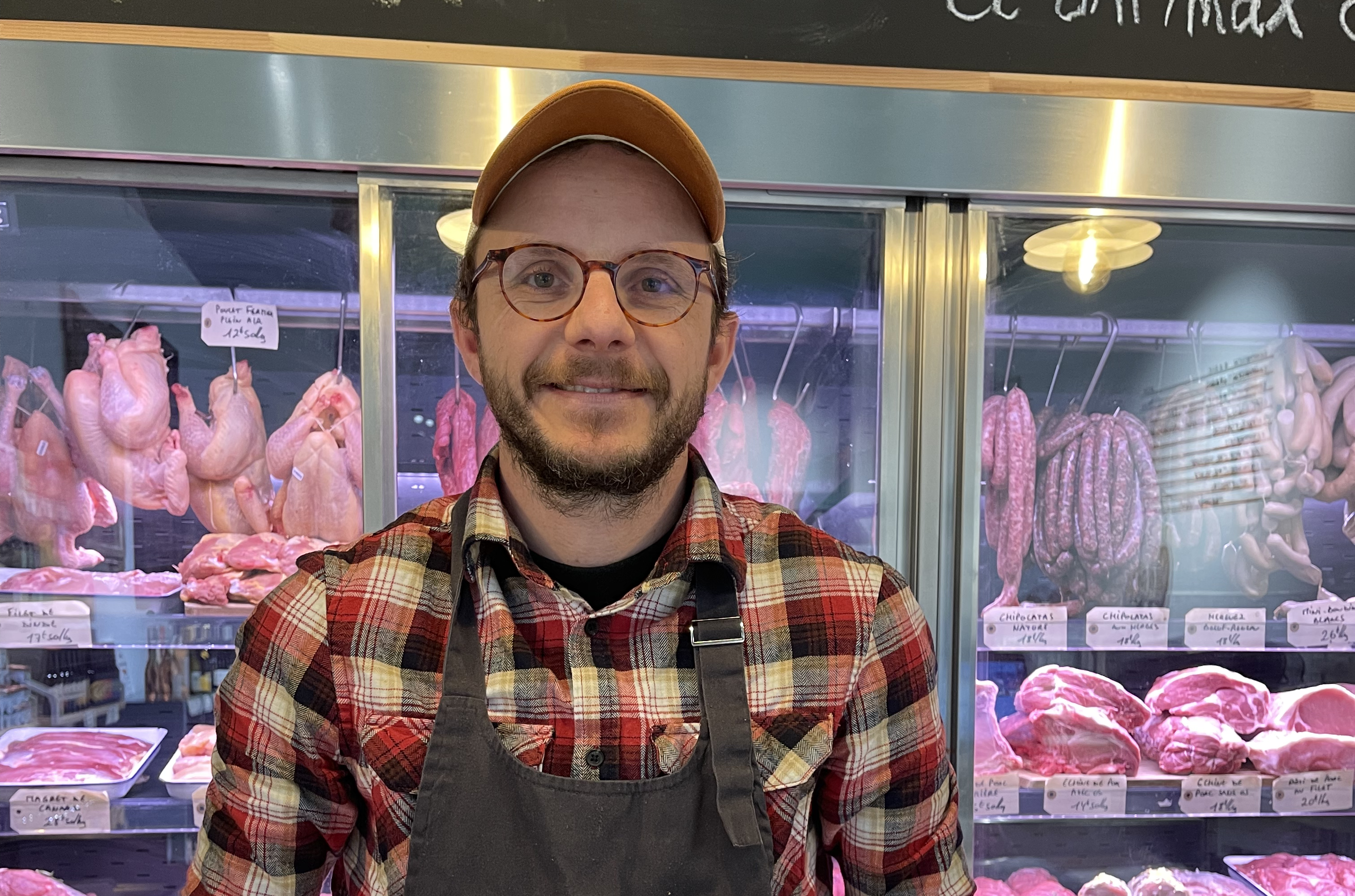 Homme avec un tablier devant des vitrines réfrigérées