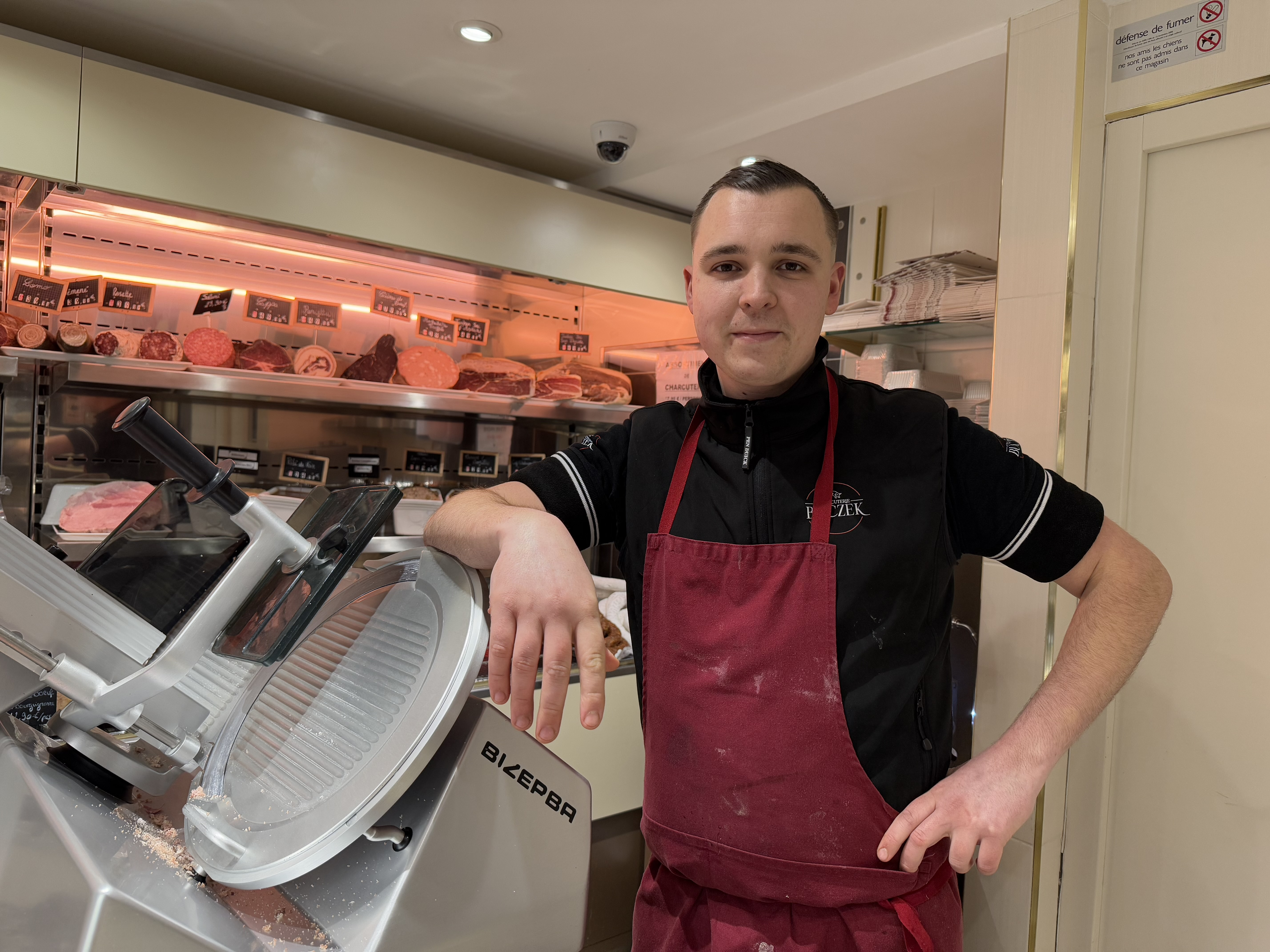 Charcutier qui se tient devant son comptoir