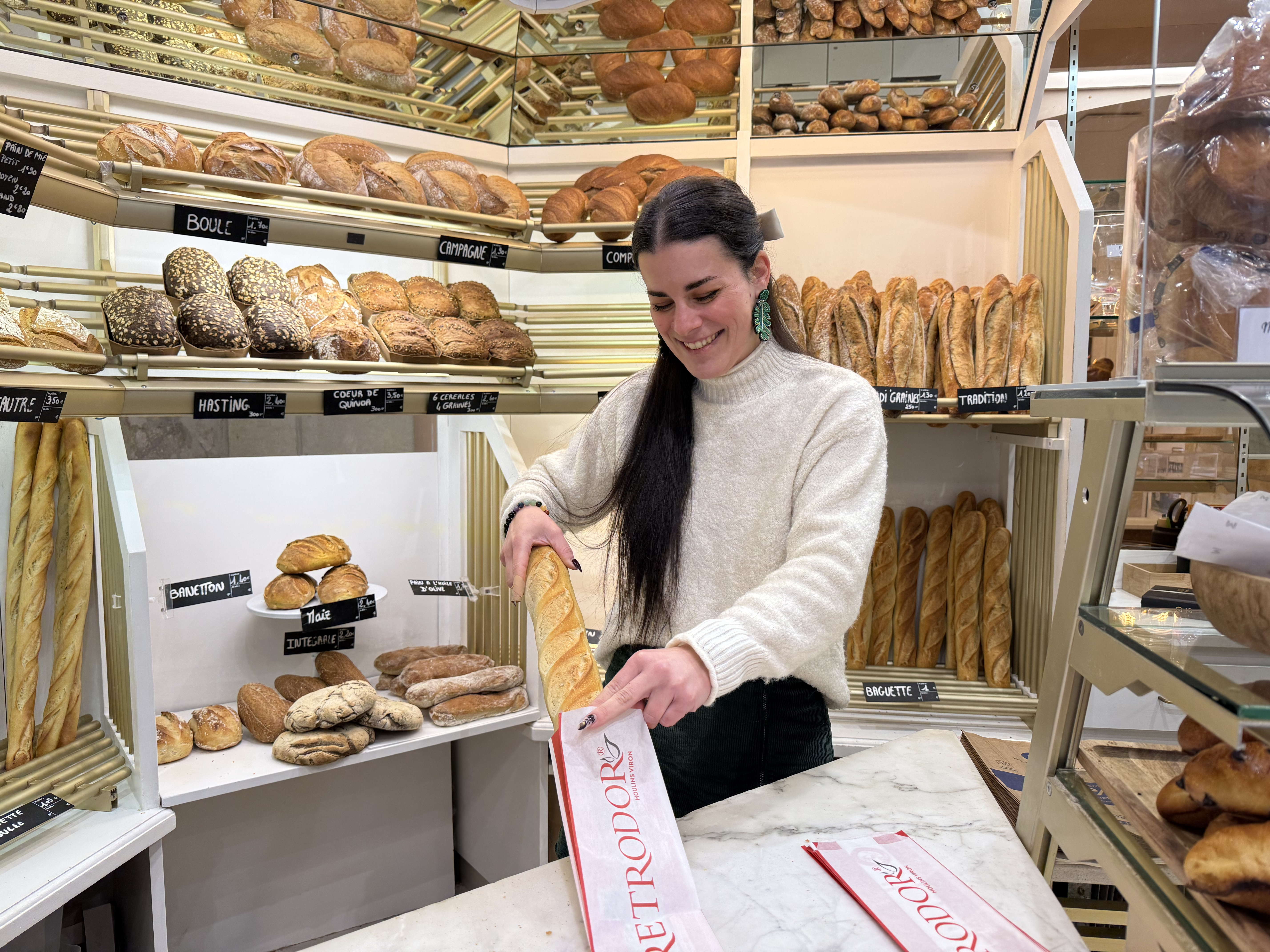 Une boulangère prépare une baguette de pain dans un sachet