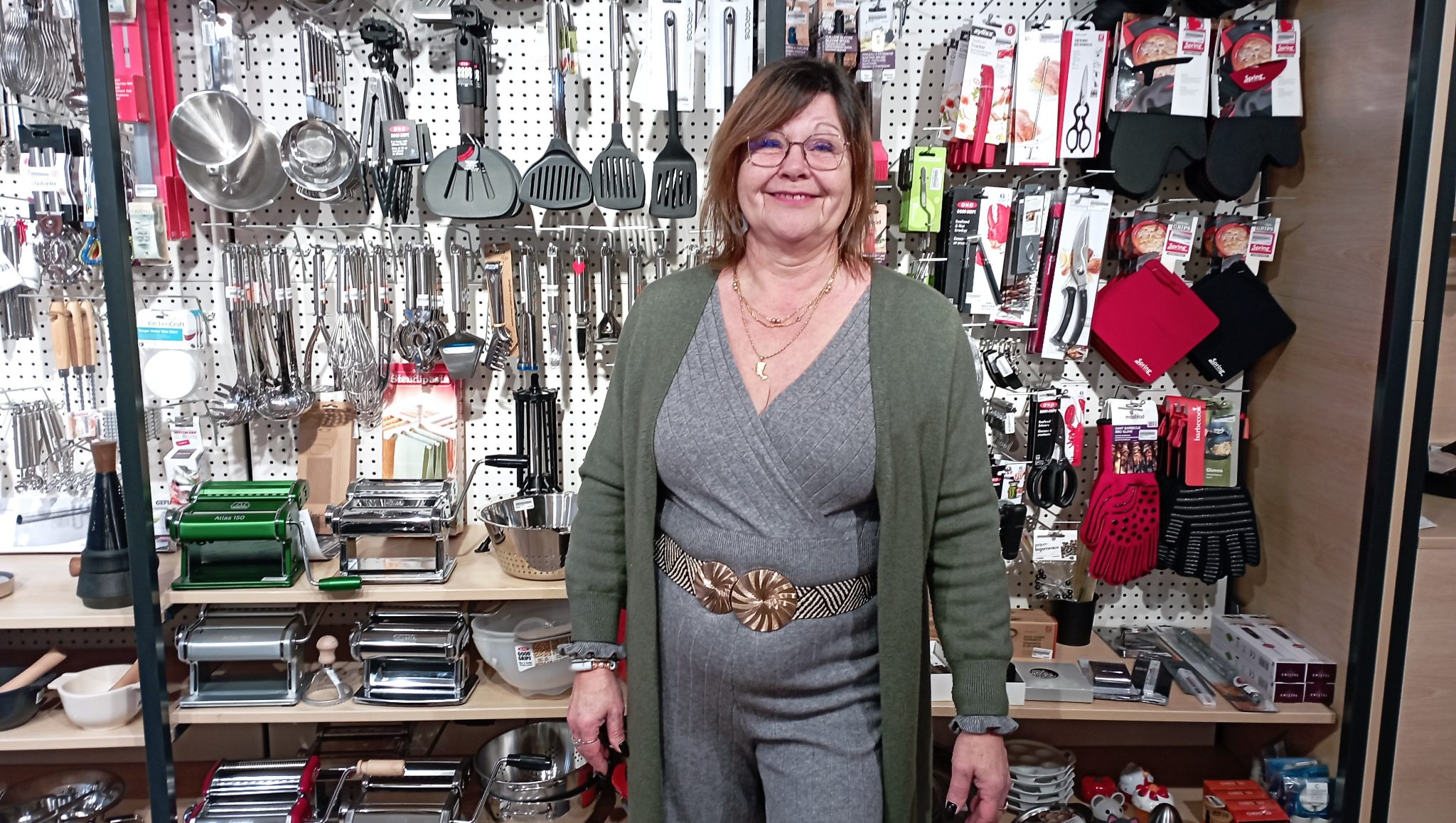 Femme qui pose devant un rayon d'ustensiles de cuisine