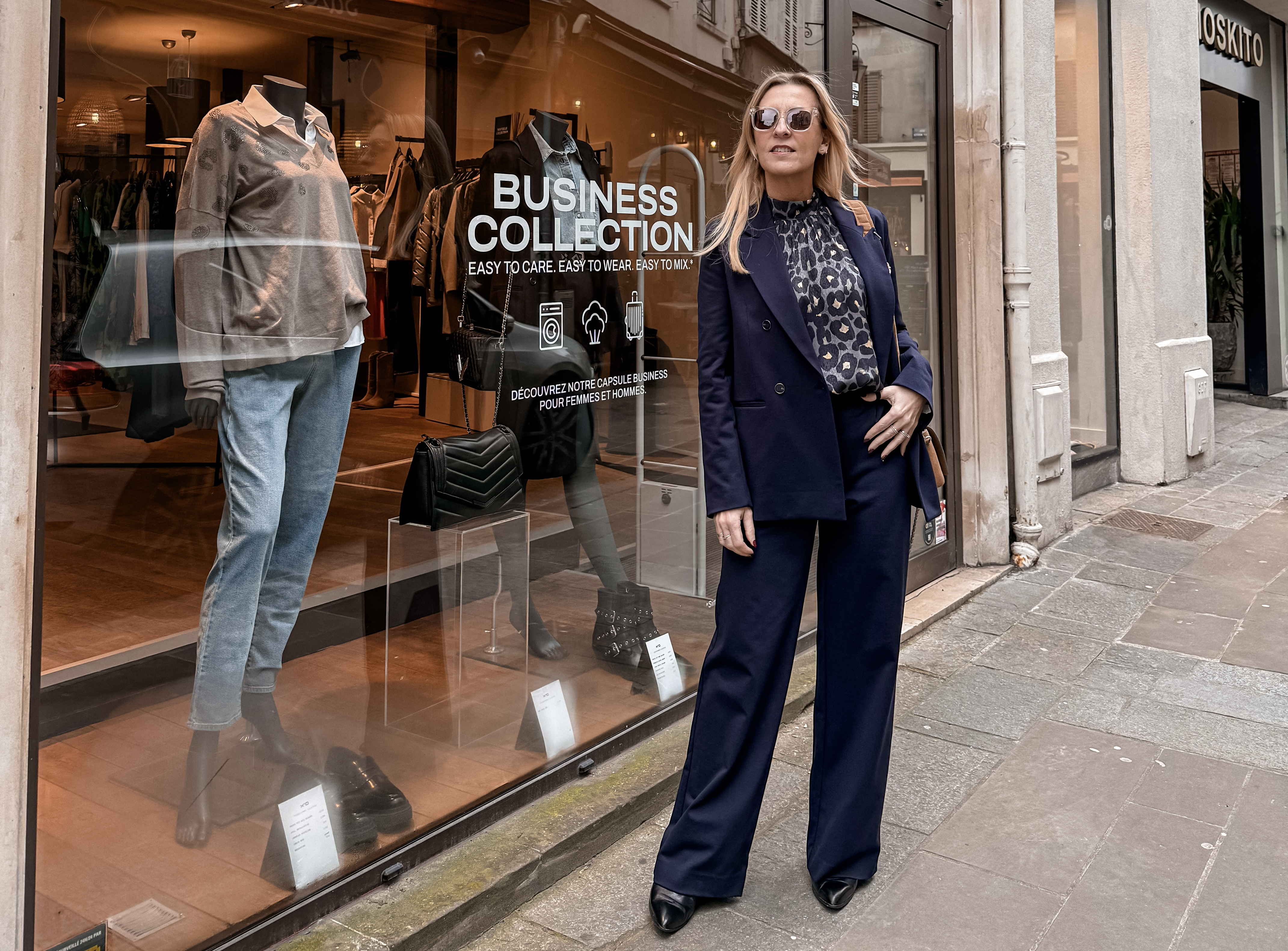 Femme qui pose devant une vitrine de vêtements