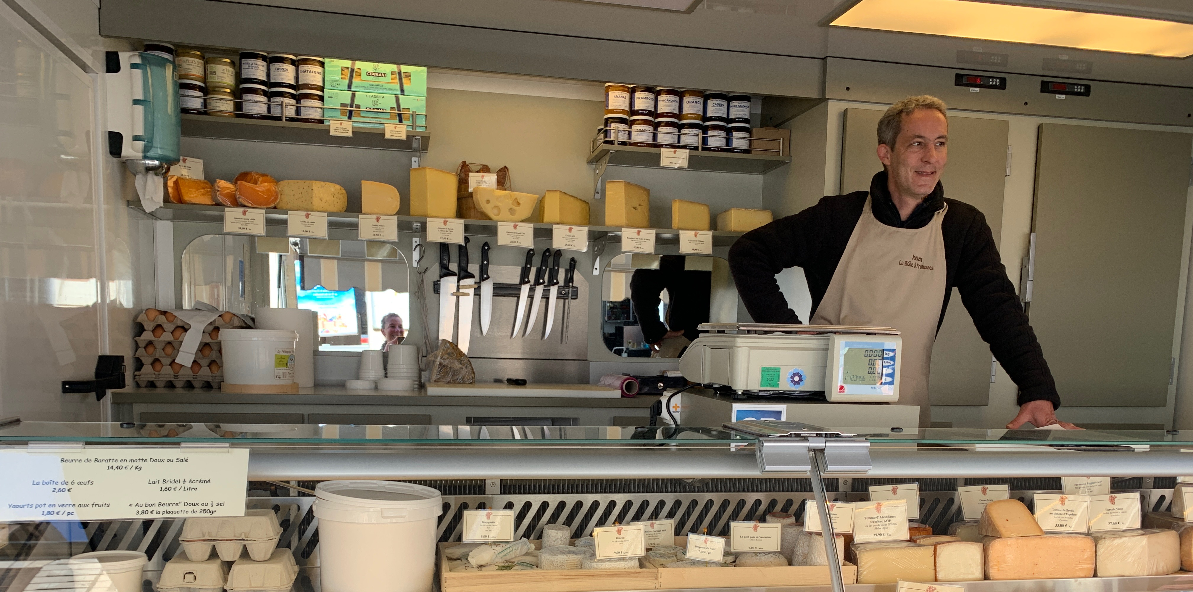 Homme prêt à servir derrière une vitrine de fromages