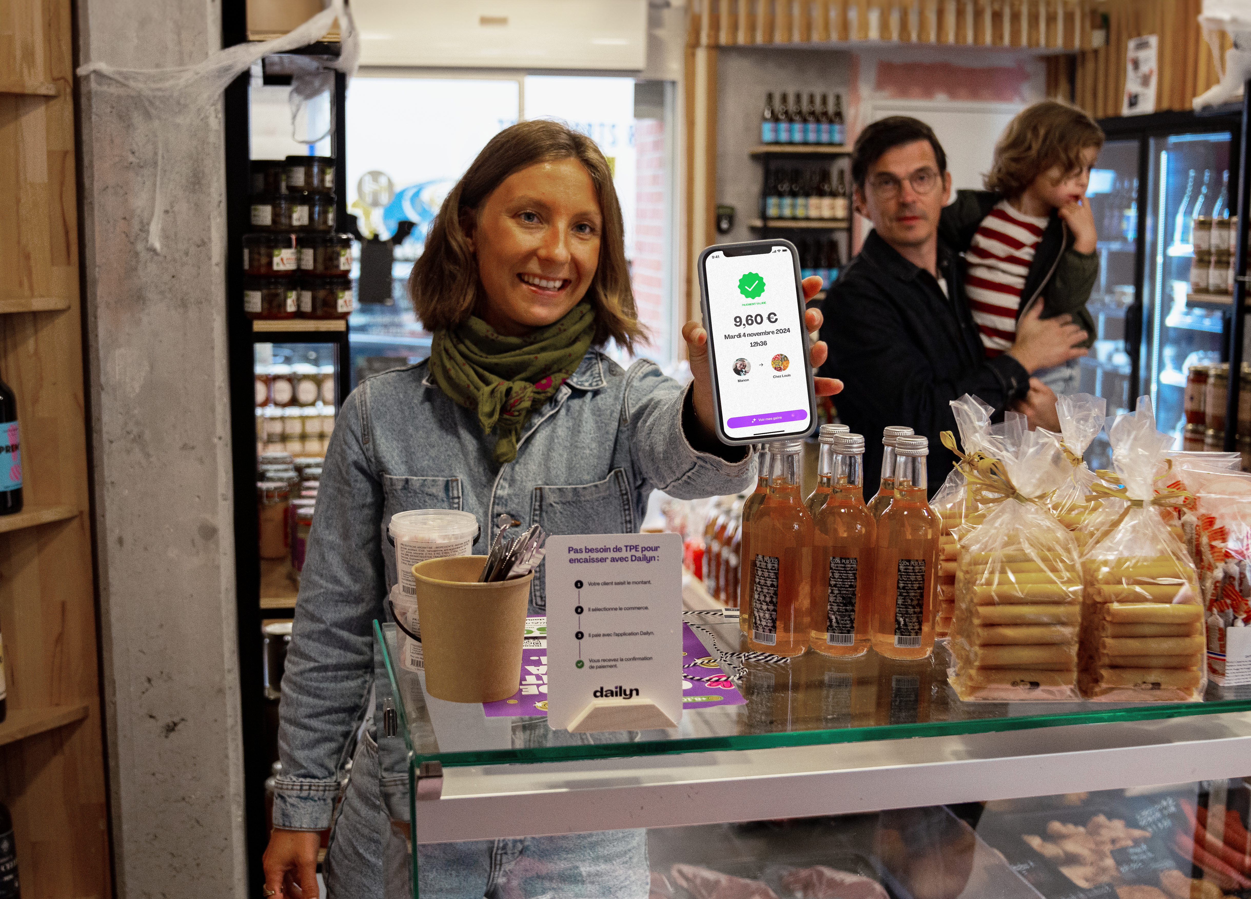 Une femme montre l'app Dailyn à un commerçant