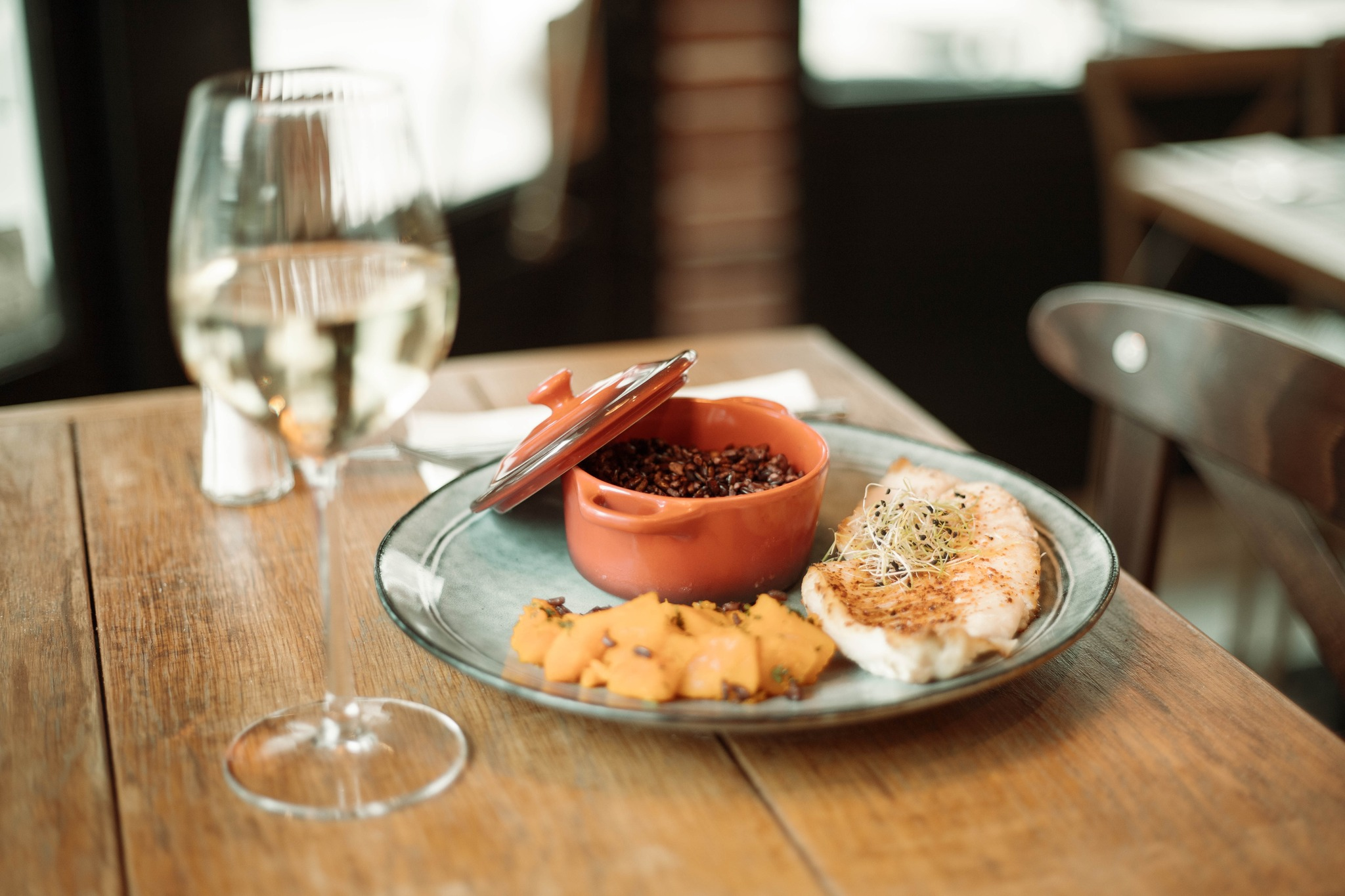 Une assiette avec un morceau de blanc de poulet, de la patate douche et des lentilles, accompagné d'un verre d'eau
