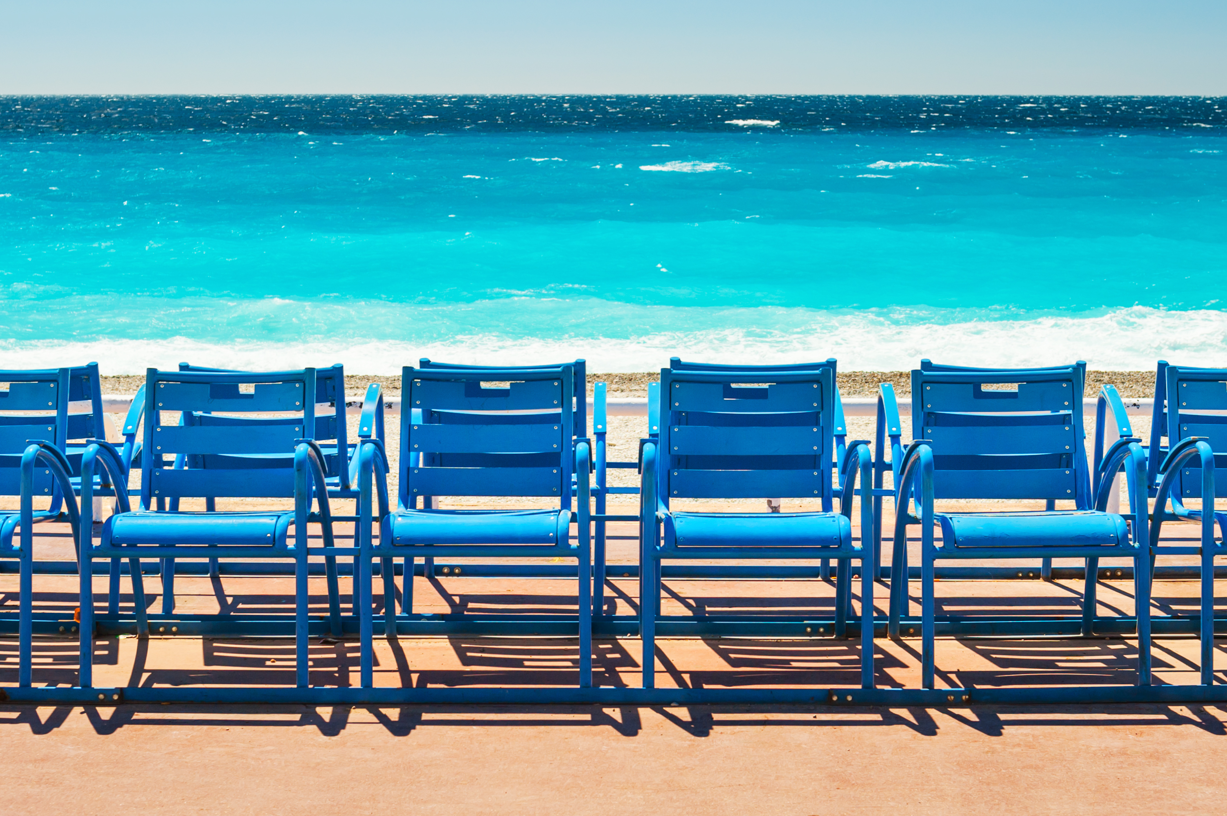Chaises bleues alignées face à la mer