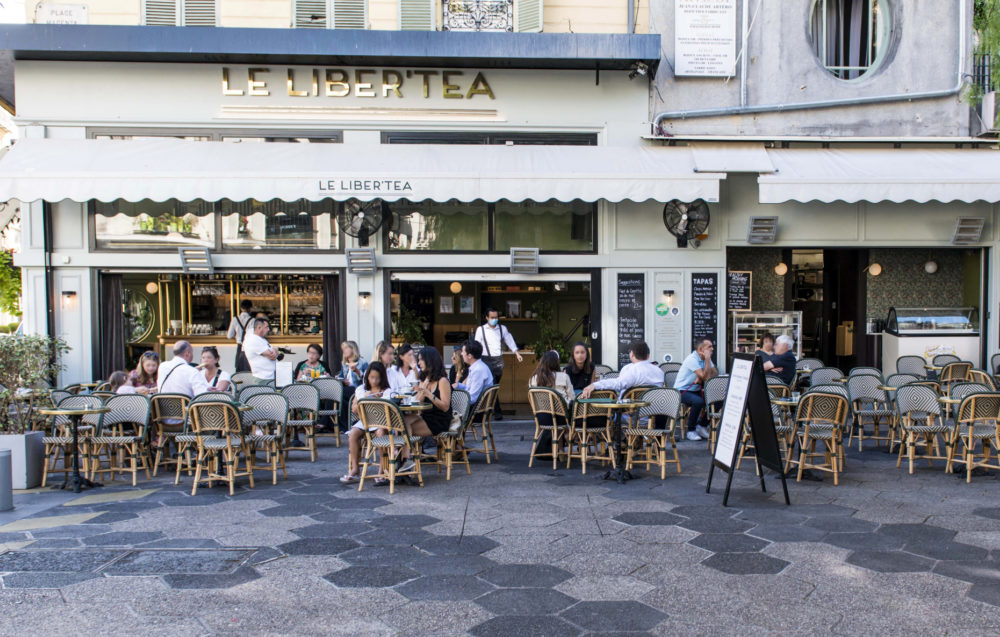 Terrasse animée avec des clients attablés et des serveurs en mouvement