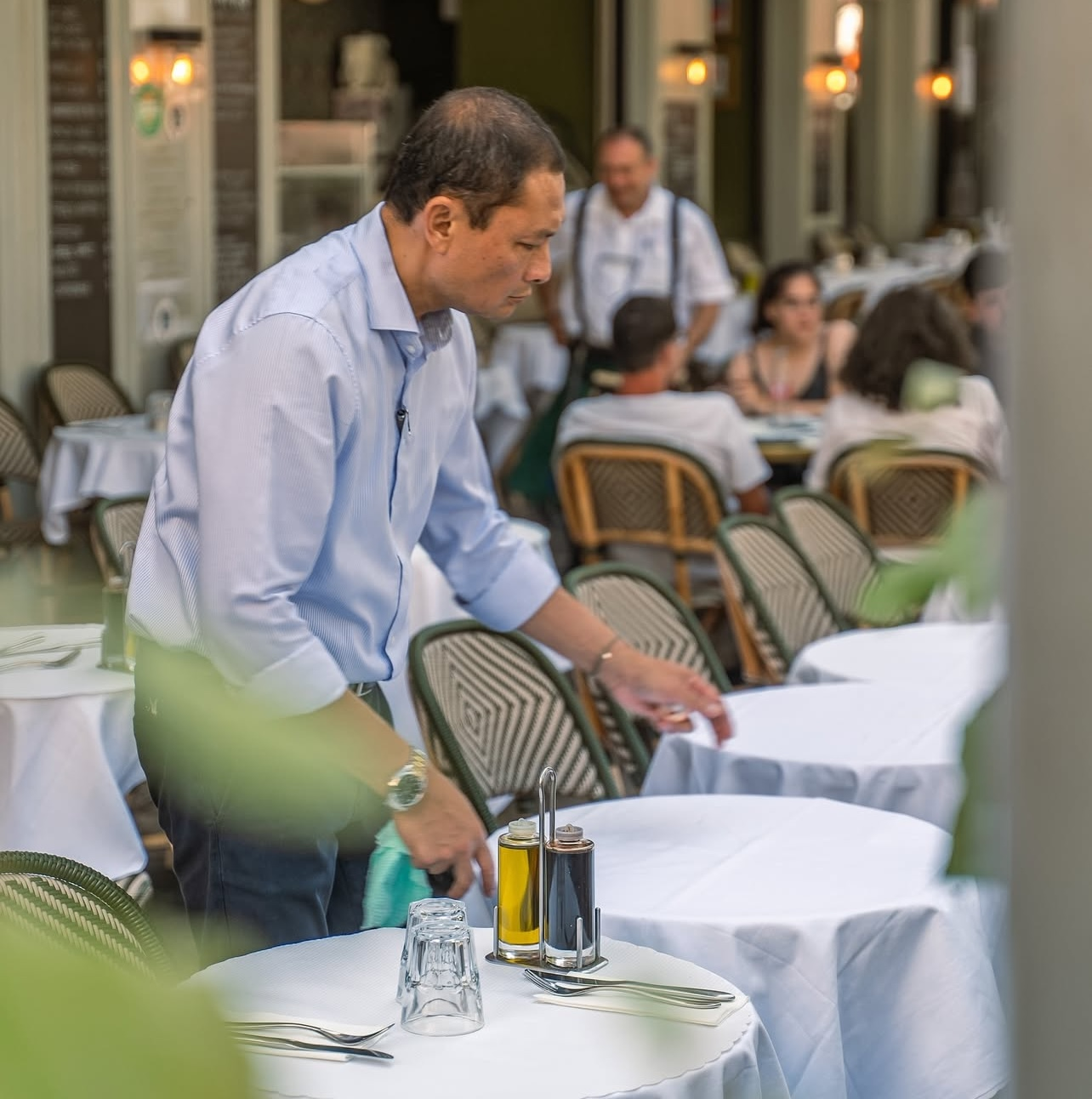 Un serveur dresse une table sur une terrasse animée