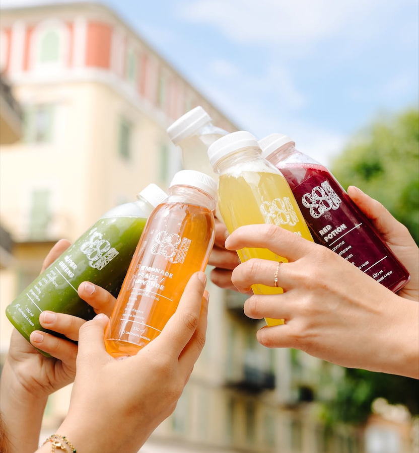 Cinq mains tenant des jus et trinquant