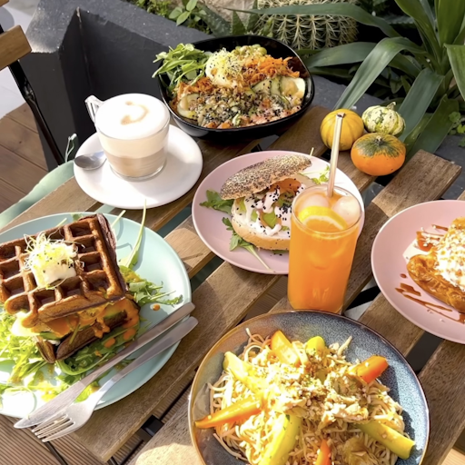 Table avec divers assiettes sucrées et salées ainsi qu'un jus d'orange et une boisson chaude