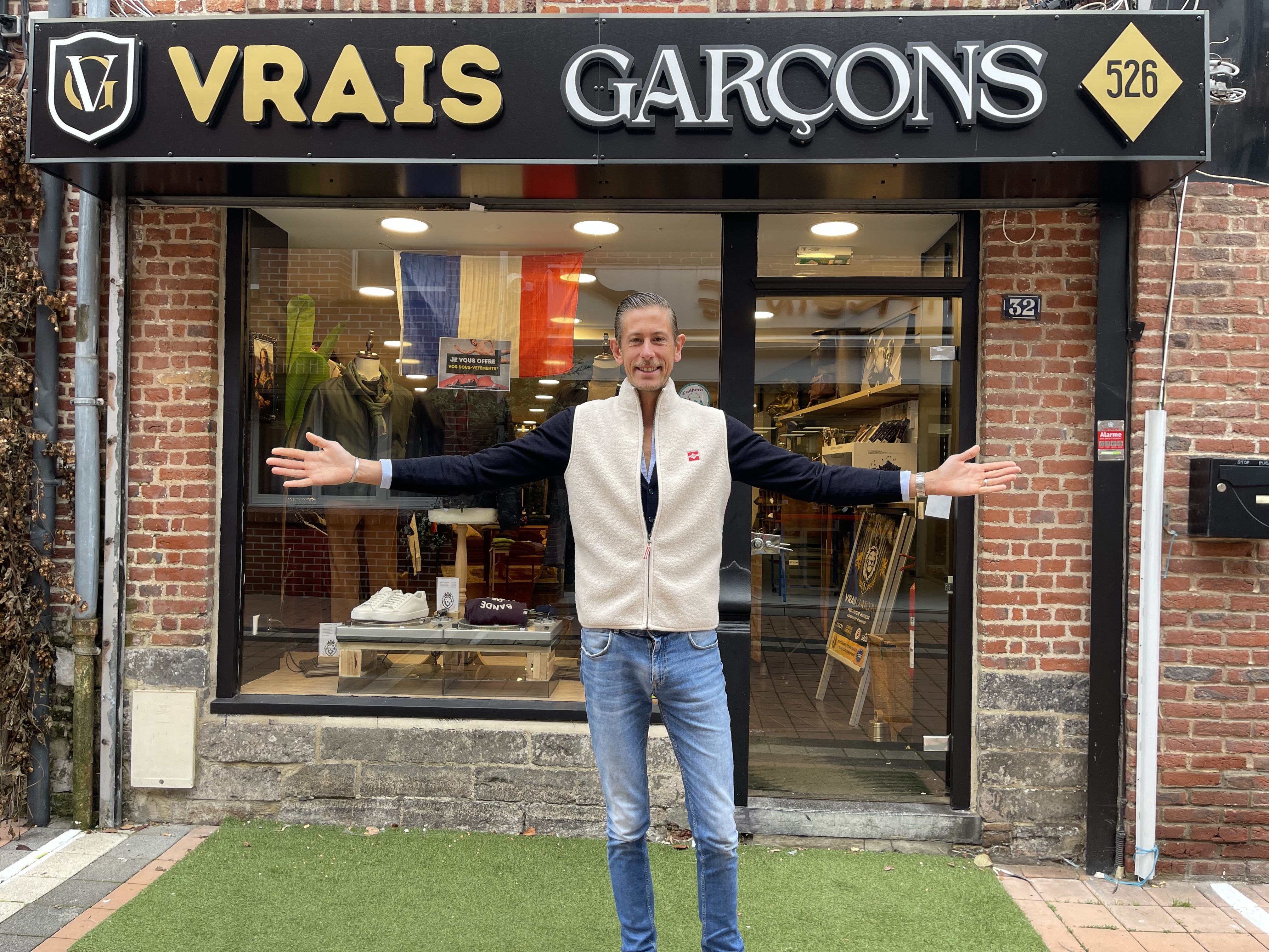 Un homme pose devant sa boutique